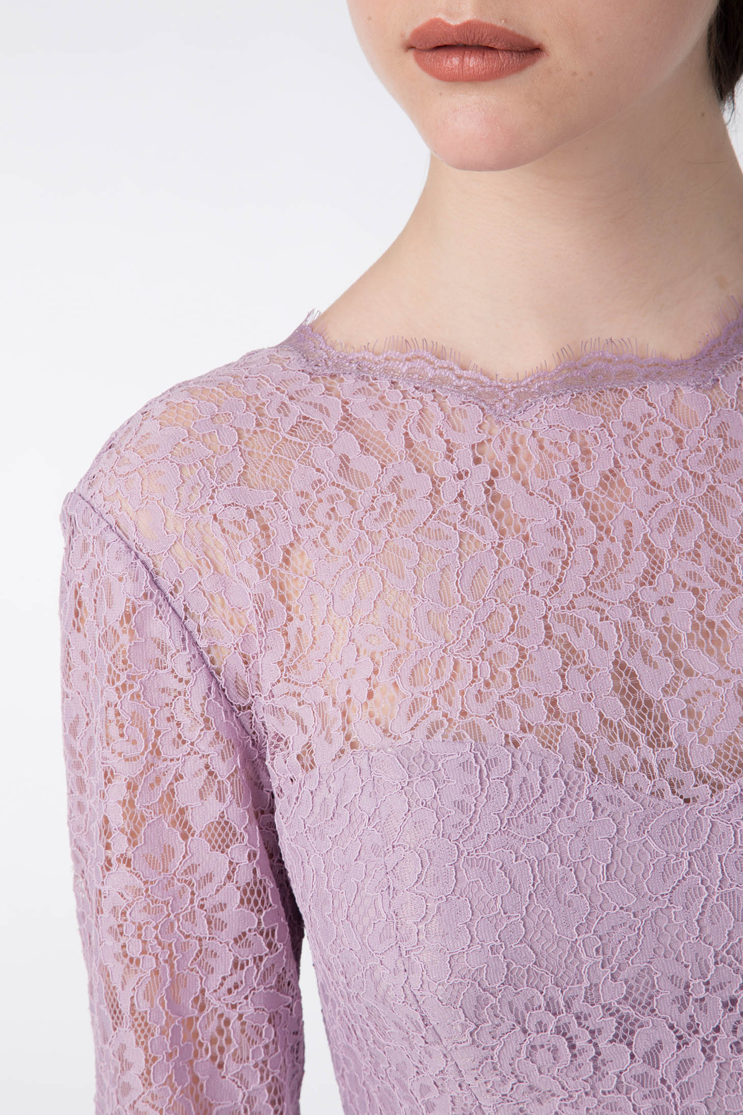A person dressed in a vintage piece—the Antonio Croce Ambeta Long-Sleeve Lace Dress, showcasing intricate floral patterns. The dress features a high neckline with subtle frayed detailing, offering an elegant look. The image highlights the upper torso, providing a close-up view of the lace texture.