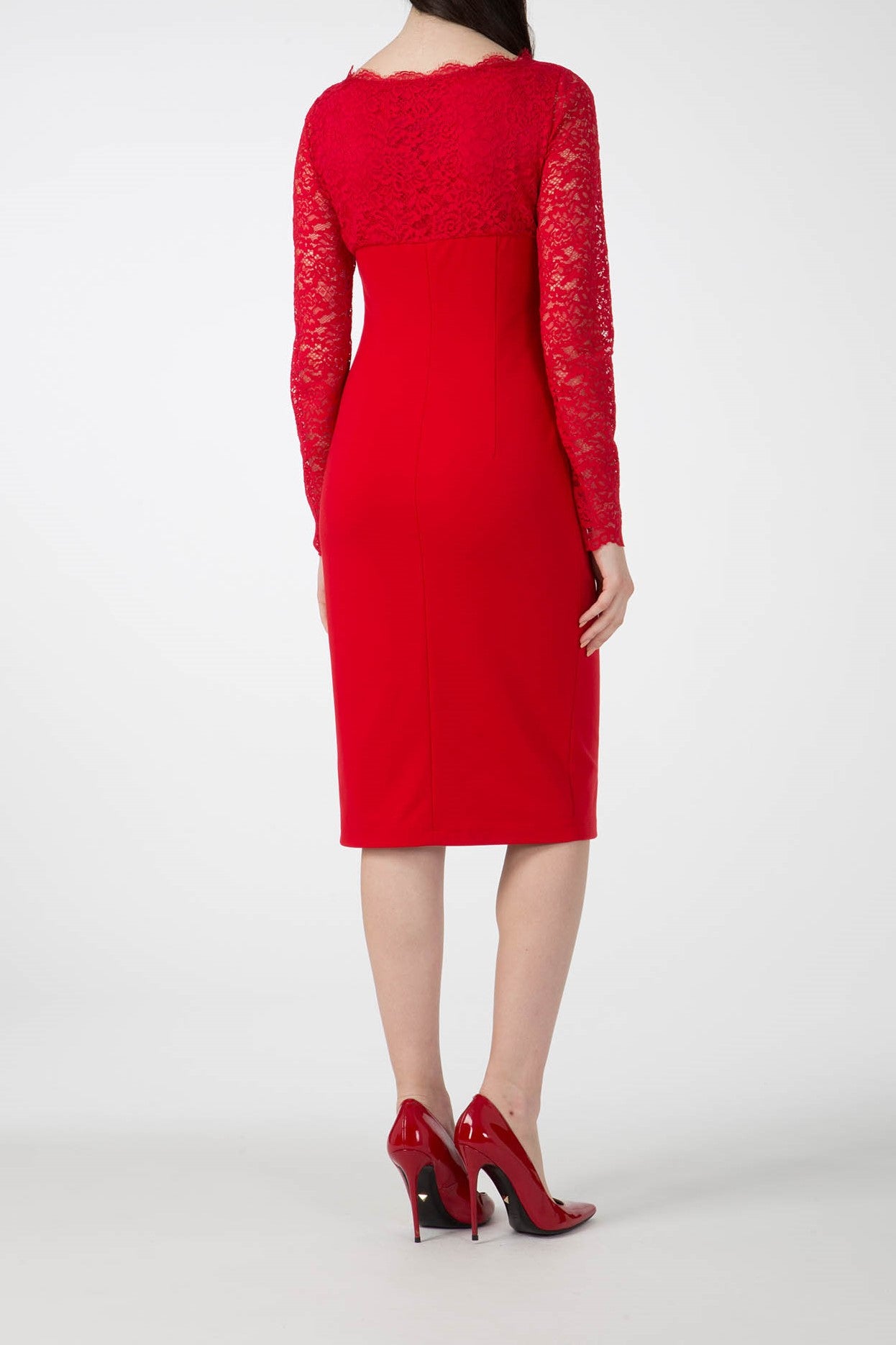 A woman is depicted from behind, wearing the Antonio Croce Ampara Embroidered Lace Dress, which is an elegant red ensemble with delicate lace fabric adorning the long sleeves. Her long, dark hair cascades down her back as she stands gracefully in red high heels against a simple white backdrop.