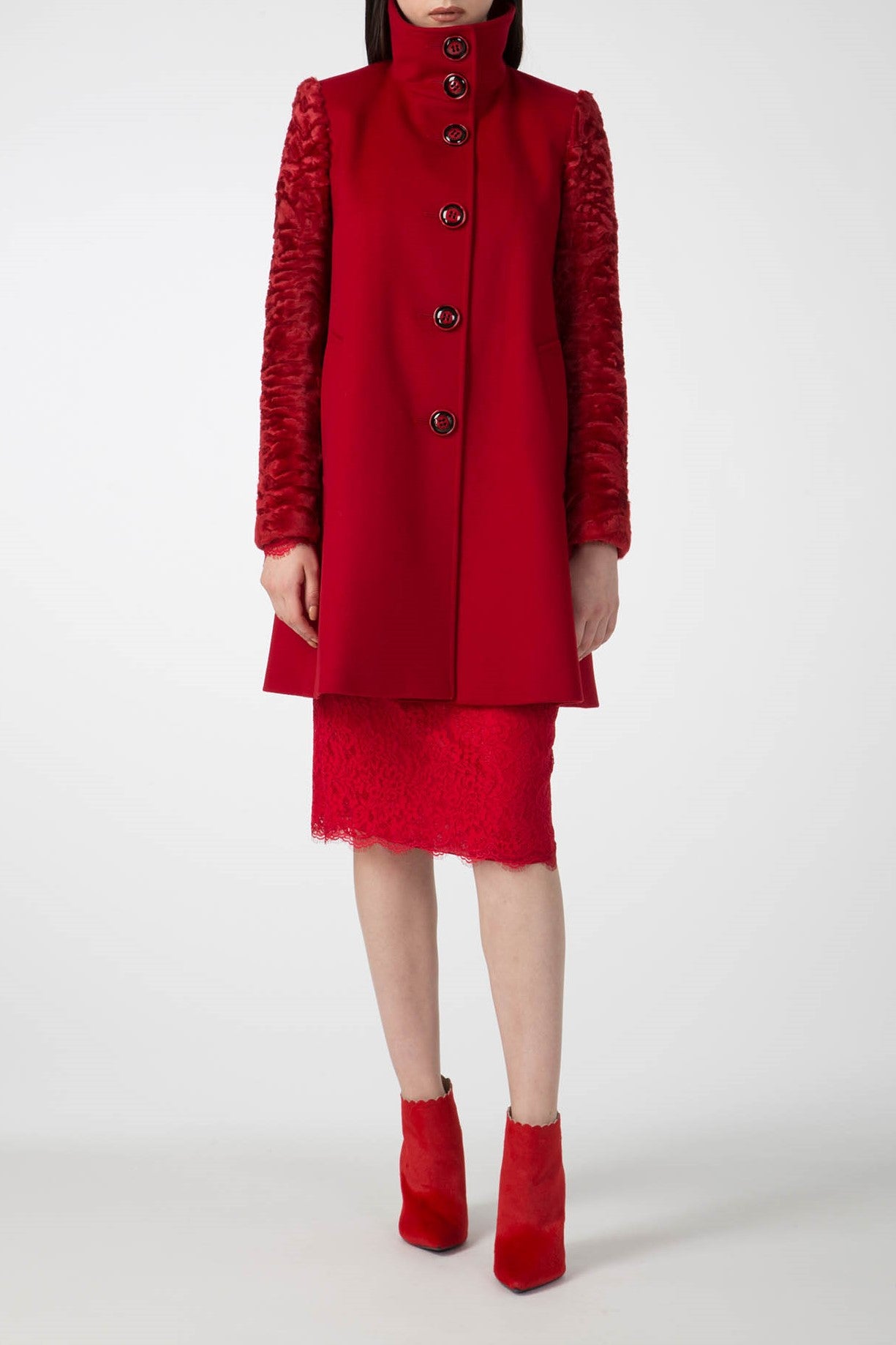 A person dressed in the Antonio Croce Callie Textured Coat with Contrast Sleeves, a matching red skirt, and red ankle boots stands against a plain white background, radiating the charm of a vintage piece.