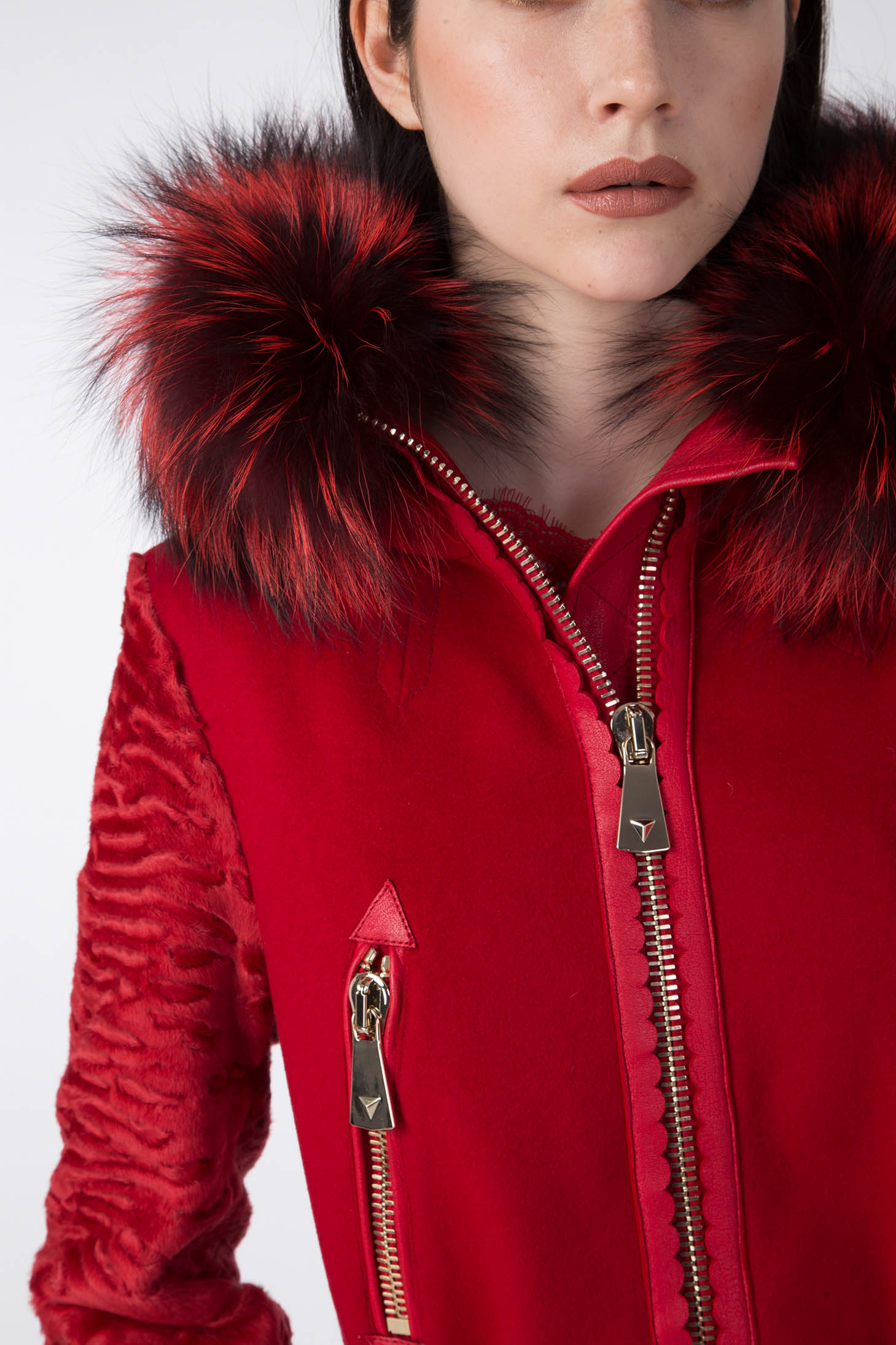 A person is seen wearing an Antonio Croce Catrina Coat, distinguished by textured sleeves and a furry collar. This vintage piece by Antonio Croce features zippers and a high collar with striking black and red fur accents. The photo captures only the individual's upper torso and lower face.