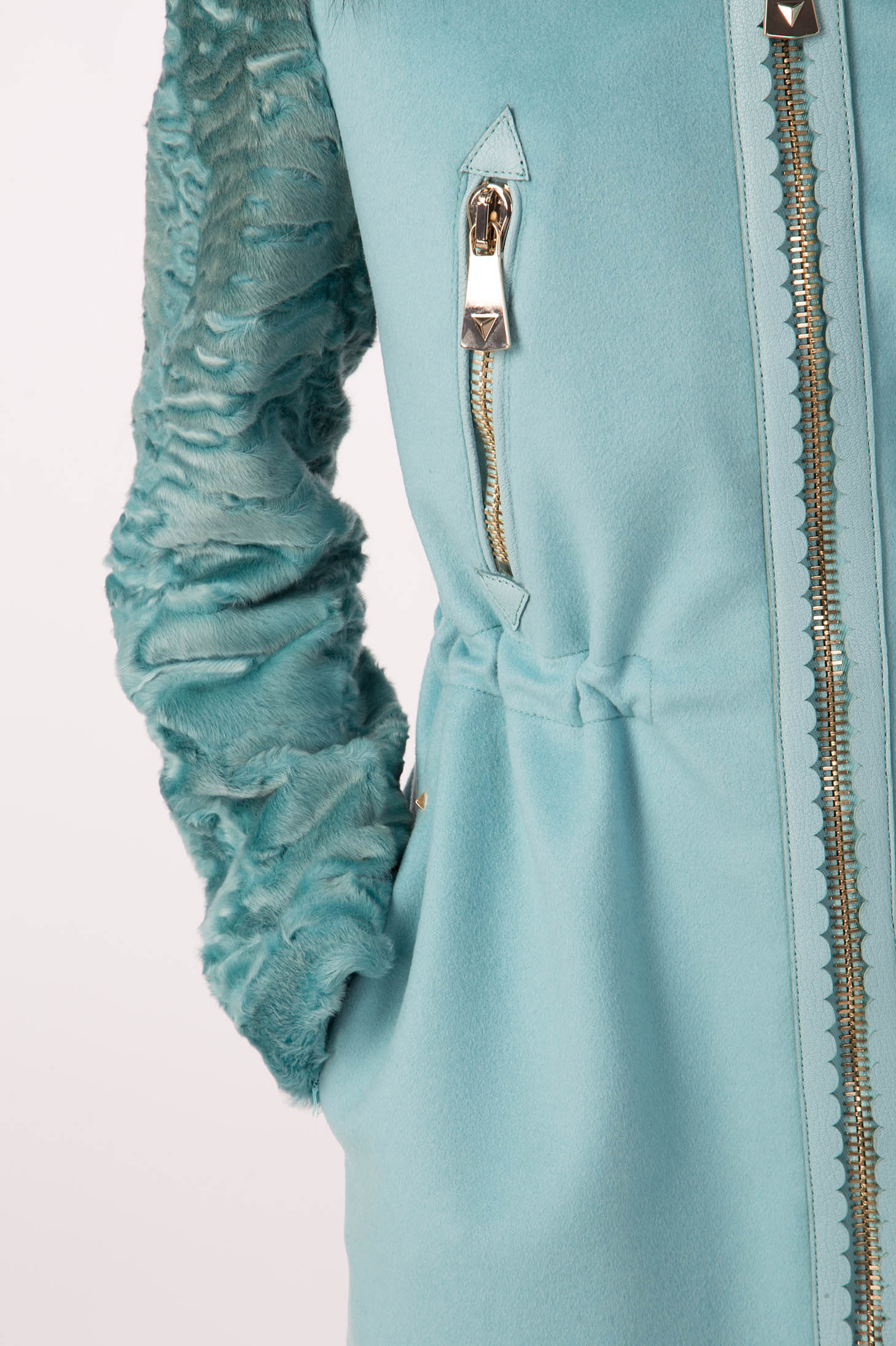 Close-up of the Antonio Croce Catrina Coat, a light blue coat featuring textured sleeves and zipper details. This bold design by Antonio Croce includes a gathered waist and a zippered pocket with a silver pull tab, offering a unique style element. The fabric looks soft and luxurious, ideal for those in search of standout fashion.