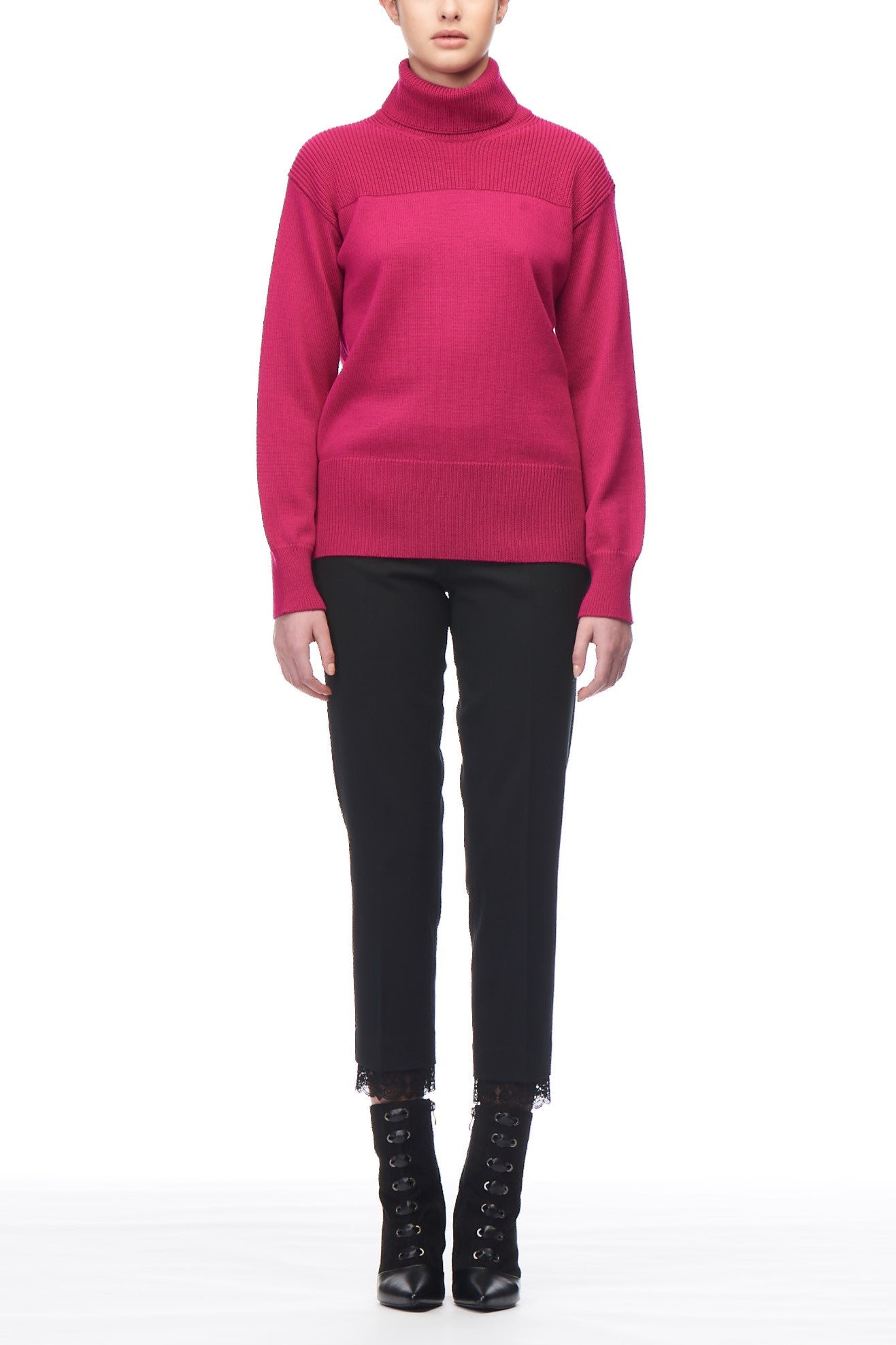 A person wearing a vibrant pink Fuzzi Woman Turtleneck Sweater, paired with black pants and black lace-up ankle boots, stands against a plain white background. The outfit exudes a modern style by combining the bold color of the sweater with sleek, elegant footwear.
