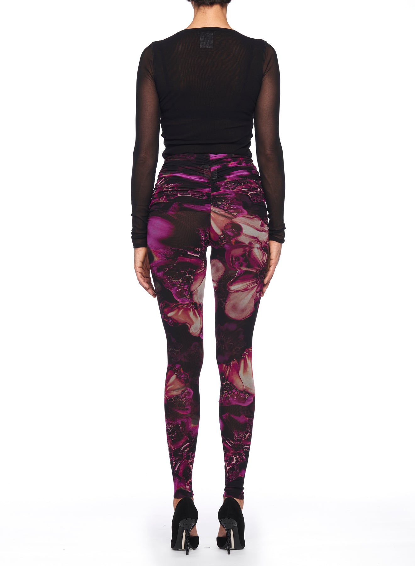 A person wearing a black long-sleeve top pairs it with the Fuzzi Woman Leggings from Fuzzi, showcasing an intricate abstract floral print. Black high-heeled shoes complete the ensemble, all against a plain white background.