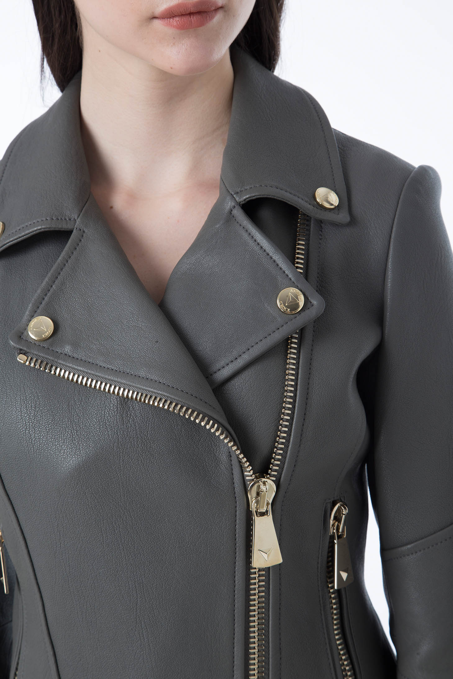 A person wearing the sophisticated Antonio Croce Ginette Jacket, characterized by its elegant gray leather and vintage gold hardware zippers and buttons. The image emphasizes the upper torso, showcasing the intricate details of this stylish piece from Antonio Croce.