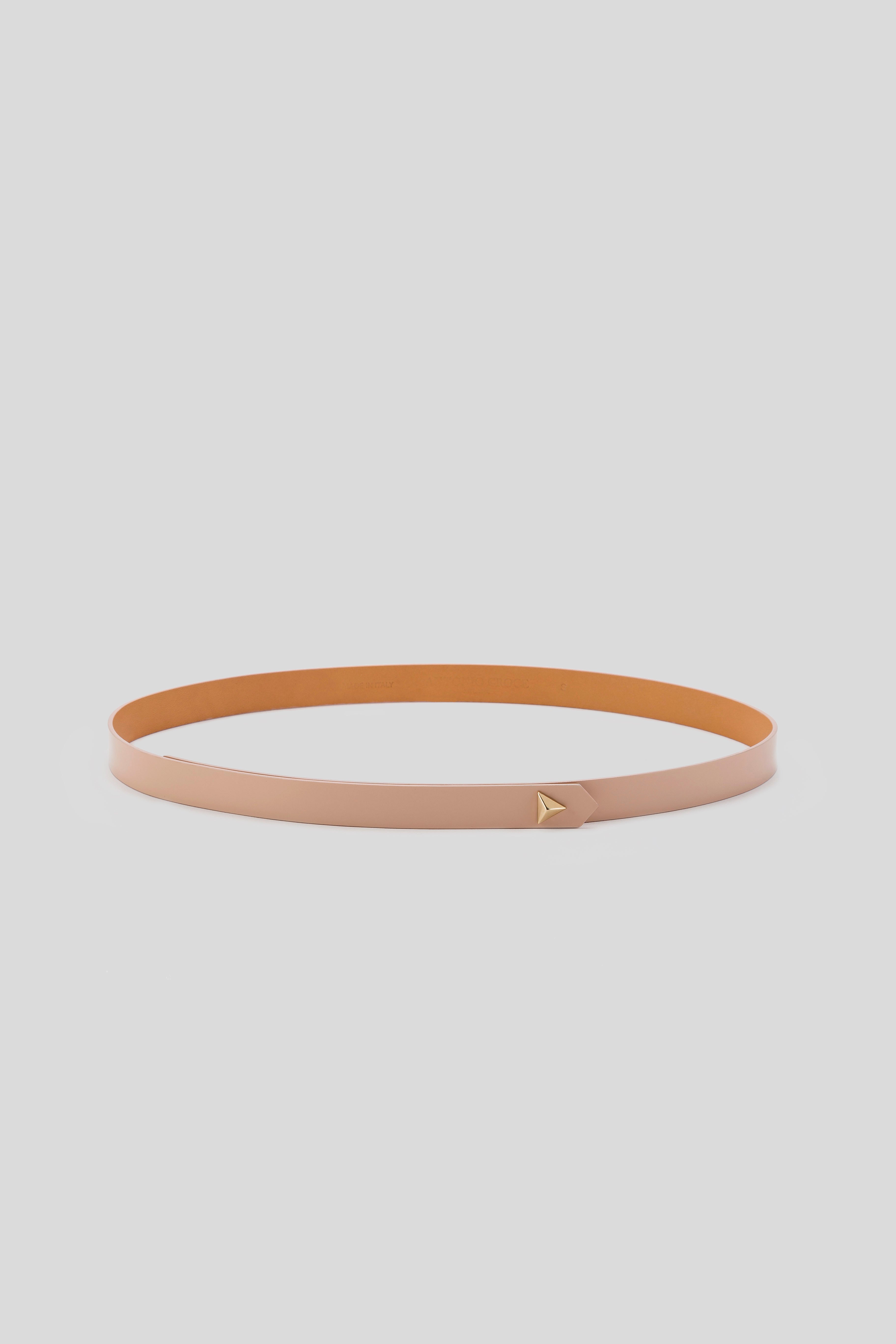 The Antonio Croce Lana Thin Belt, a sleek tan leather minimalist accessory, showcases a small gold triangular buckle and is elegantly displayed against a plain white background.