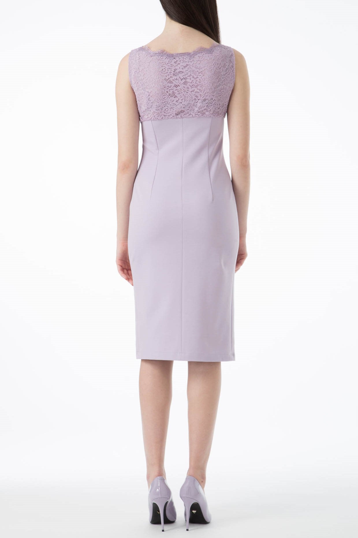 A woman confidently wears the elegant Antonio Croce Alanna Evening Dress, a stunning light purple garment featuring lace detailing on the upper back. She stands with her back to the camera against a plain white background, complemented by matching purple high heels.