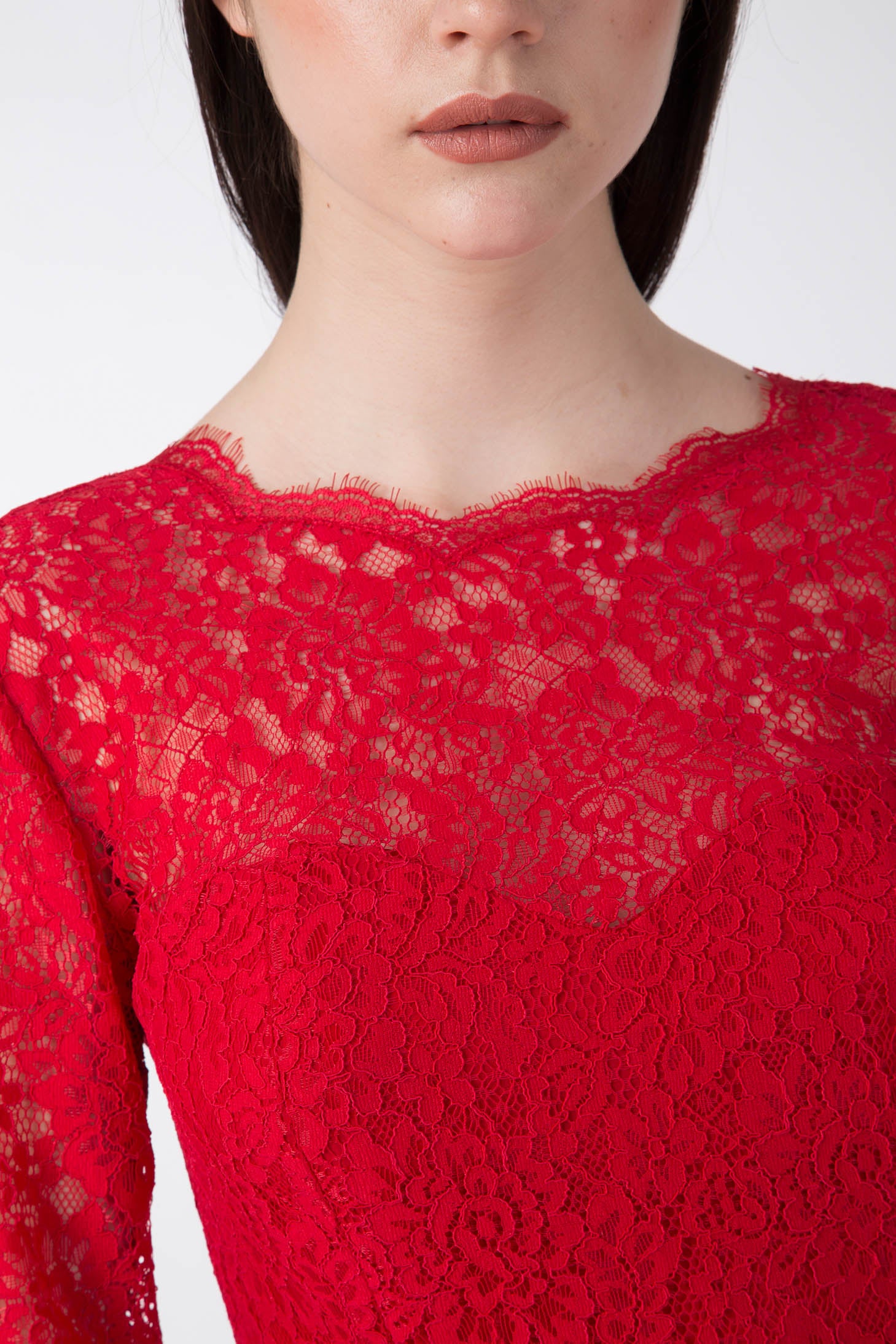 A woman is wearing a sophisticated vintage piece—the Antonio Croce Ambeta Long-Sleeve Lace Dress. The image focuses on her upper body, showcasing the dress's intricate lace pattern and scalloped neckline. Her dark, straight hair perfectly complements her neutral makeup.