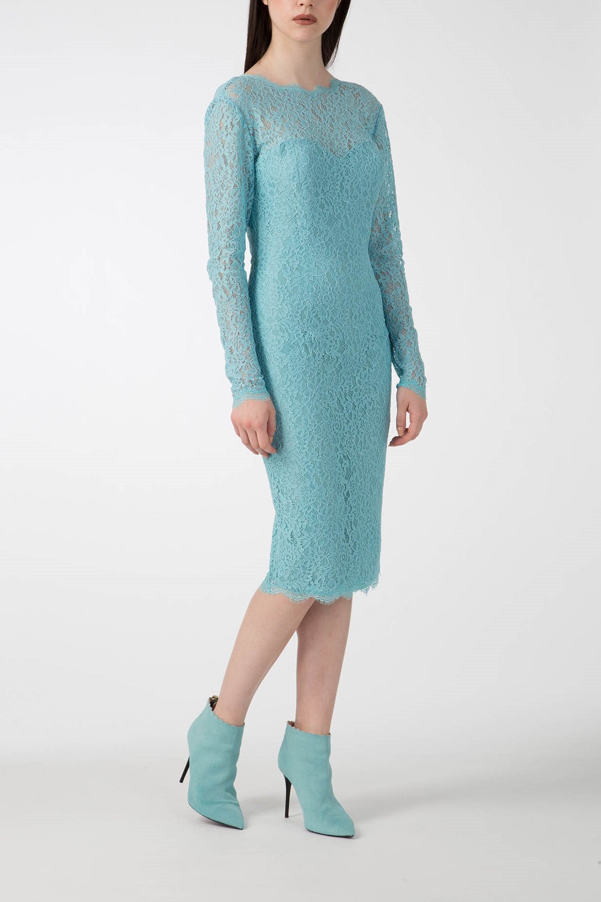 A woman showcases an elegant look in the Antonio Croce Ambeta Long-Sleeve Lace Dress, featuring a knee-length design and high neckline in light blue lace, paired with matching ankle boots. This vintage piece is set against a plain white background.