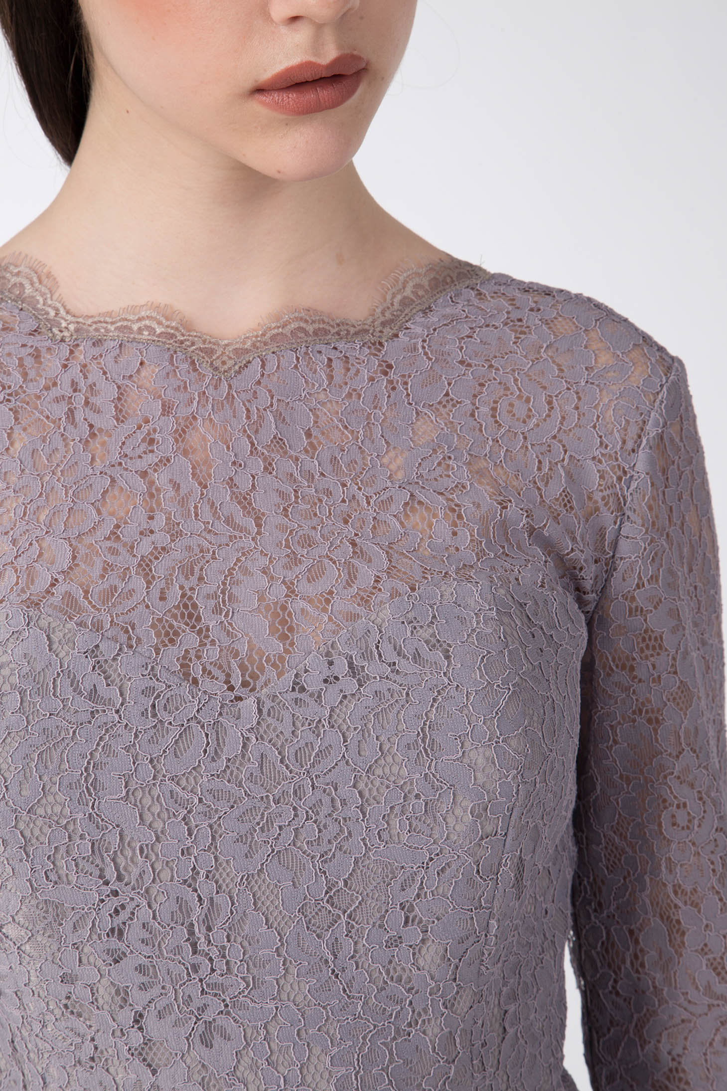 Close-up of a person wearing the Antonio Croce Ambeta Long-Sleeve Lace Dress, showcasing its elegant lavender hue and scalloped edges that emphasize the intricate floral pattern. The image highlights the torso and part of the lips, set against a neutral background.