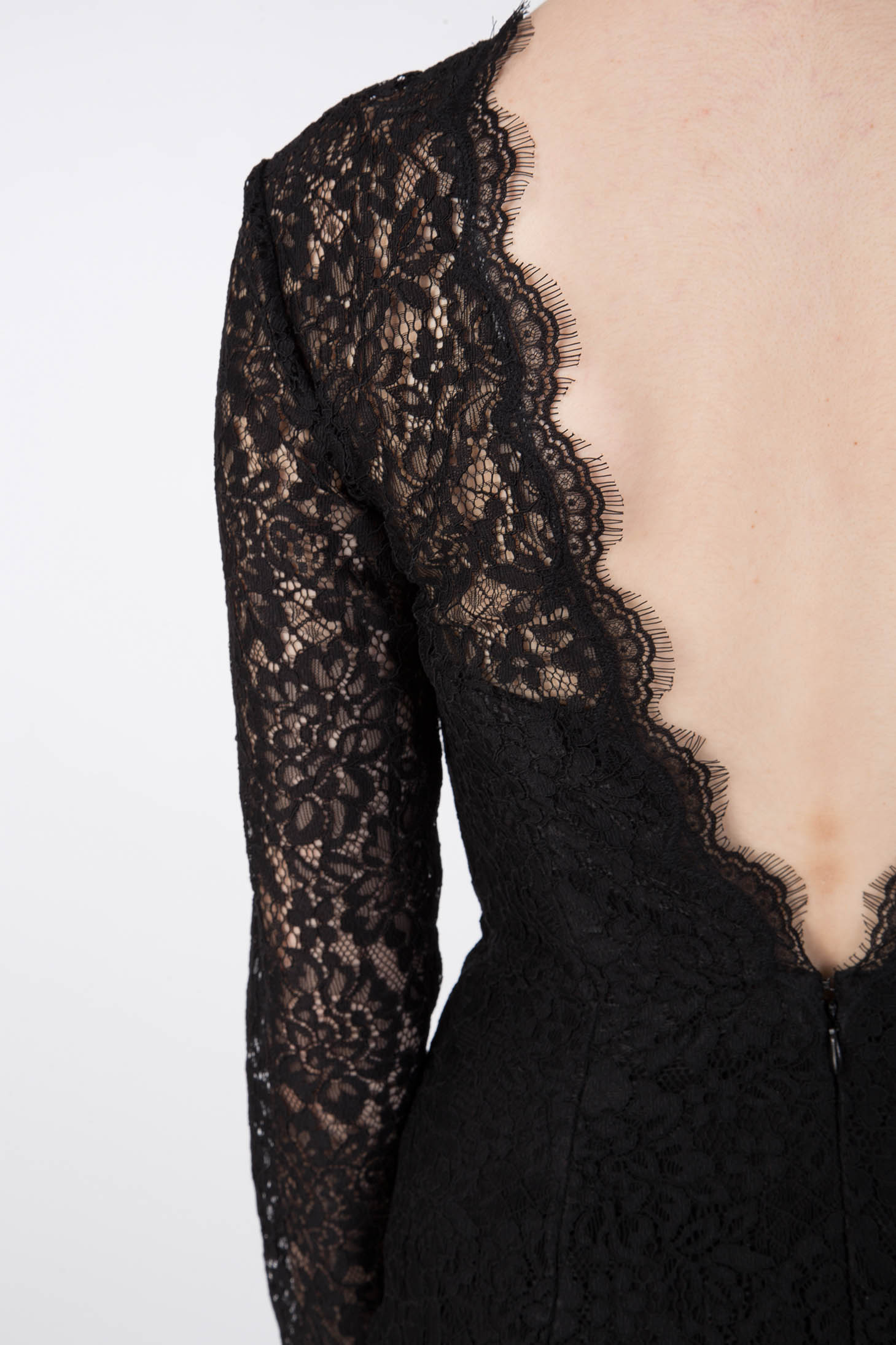 The image captures a close-up of an individual wearing the Antonio Croce Ambeta Long-Sleeve Lace Dress, exuding elegance in its black lace design. The focus is on the back of the dress, highlighting its deep, scalloped V-neckline. This vintage-inspired piece is crafted from intricate lace material adorned with a delicate floral pattern.