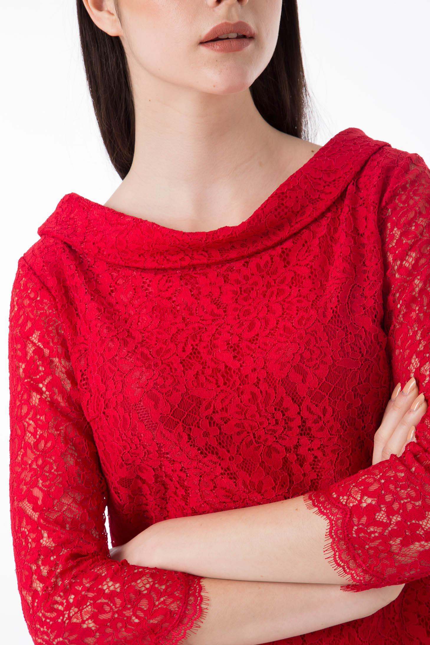 A woman with long dark hair is dressed in the Antonio Croce Ana Romantic Lace Dress, a vintage piece in vibrant red. The dress features three-quarter sleeves and a boat neckline, and she stands with her arms crossed against a plain white background, highlighting its textured floral pattern.