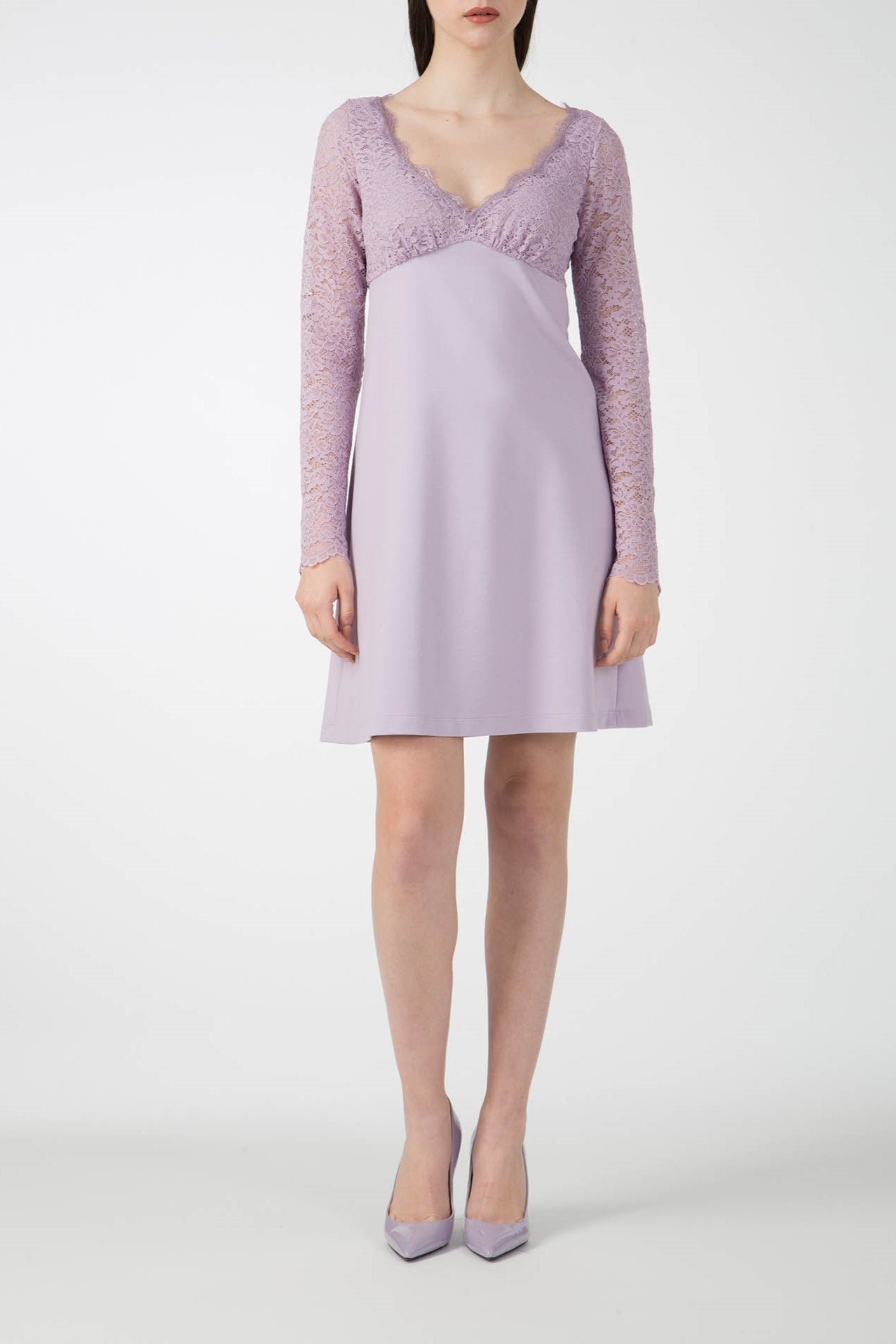 A woman wearing an Antonio Croce dress in a romantic two-tone light purple style with lace sleeves and matching heels stands against a plain white background.