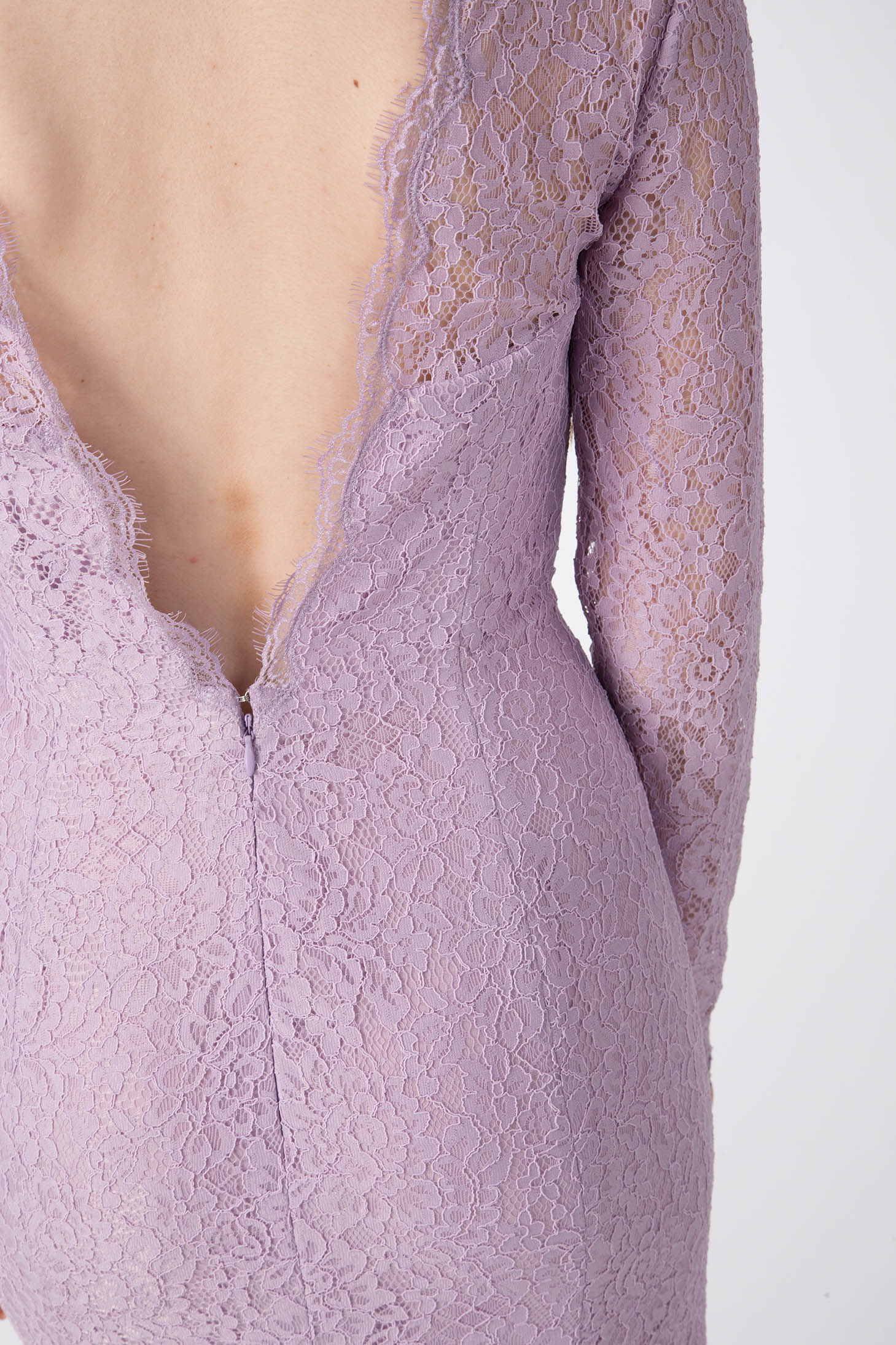 A close-up of a person in the Antonio Croce Australia Allover Lace Gown with a plunging back, showcasing the vintage design of long sleeves and intricate lace detailing against a plain light background.