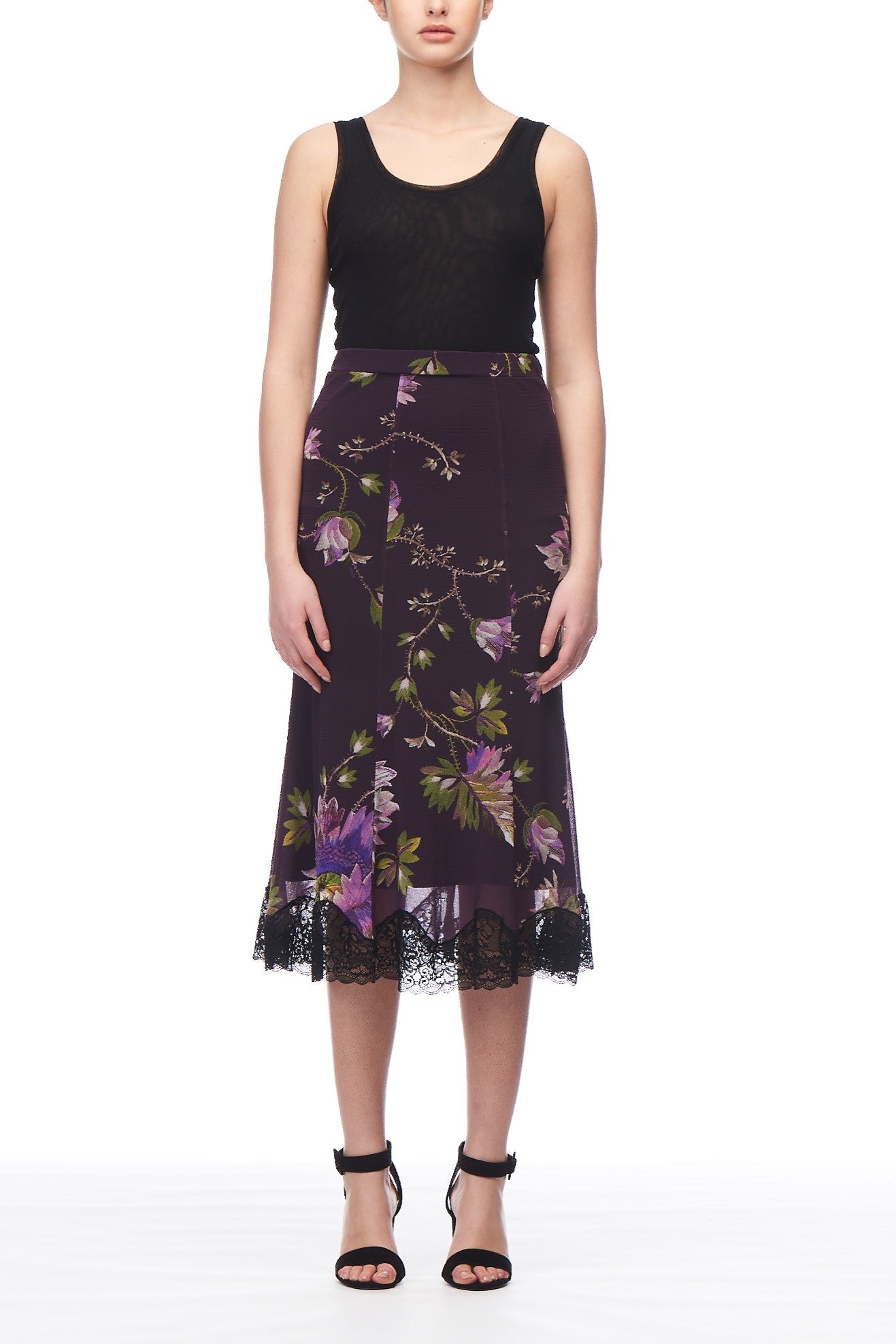 A person wearing a black sleeveless top and the Fuzzi Woman Floral Lace Trim Midi Skirt from Fuzzi in purple. They have on black high-heeled sandals, all set against a plain white background.