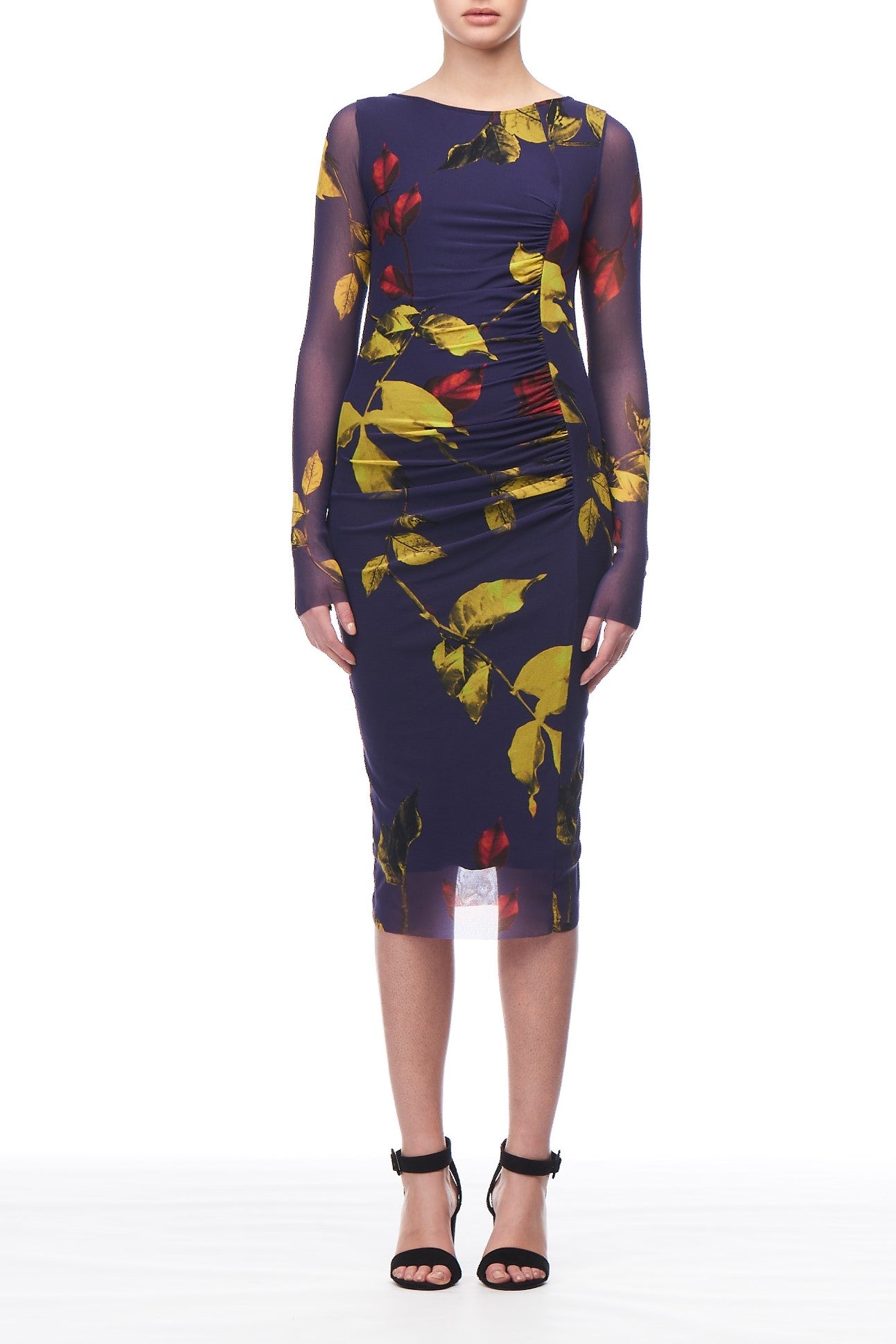 A person stands against a plain white background wearing the Fuzzi Woman Long Sleeve Floral Mesh Dress by Fuzzi, which features a form-fitting design with an elegant navy floral print accented by yellow and red patterns. This vintage-style piece gracefully falls below the knee and is paired with sleek black high-heeled sandals.