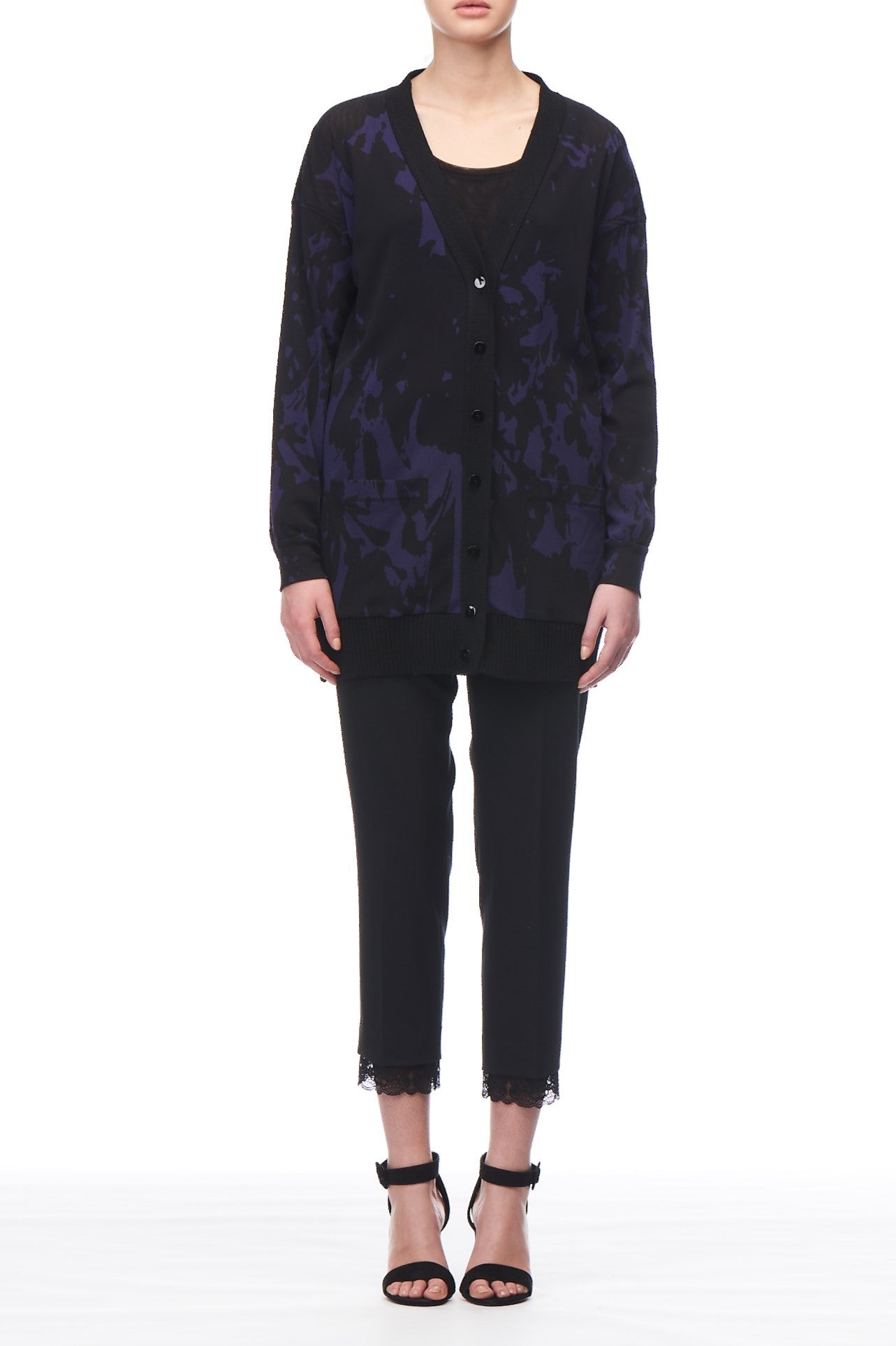 Dressed in the Fuzzi Woman Abstract Print Cardigan over a black top, paired with vintage cropped pants featuring lace trim and black high-heeled sandals, the ensemble exudes charm against the white background.