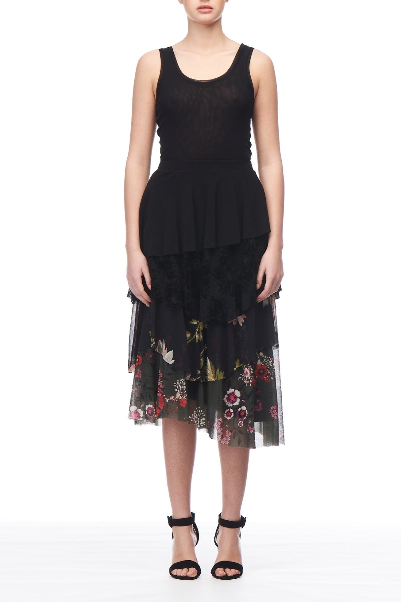 A person showcasing the Fuzzi Woman Layered Floral Skirt, a truly wearable piece of art, pairs it with a sleeveless black top as they pose against a white background. They complete their statement look with black open-toed heels.