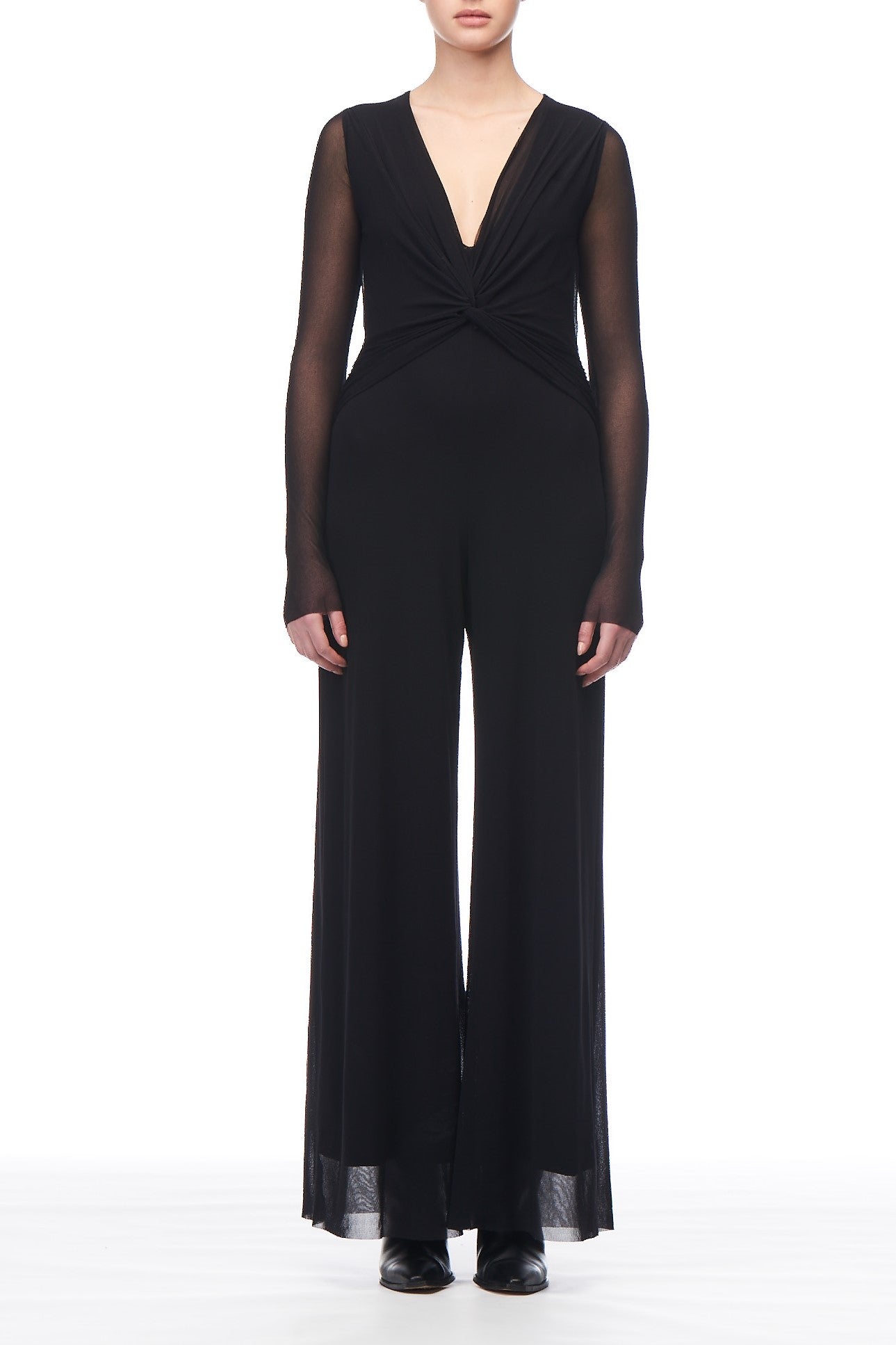 A person radiates effortless elegance in the Fuzzi Woman Tulle Long Sleeve Jumpsuit, featuring a deep V-neckline and flared pants. This versatile piece is perfectly complemented by sleek black shoes, all set against a plain white background.