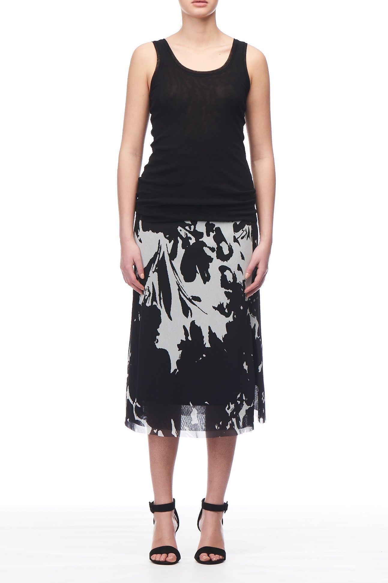 A person wearing a striking look: the Fuzzi Woman Relaxed Fit Top paired with a black and white patterned midi skirt. They are also wearing black high-heeled sandals against a plain white background.