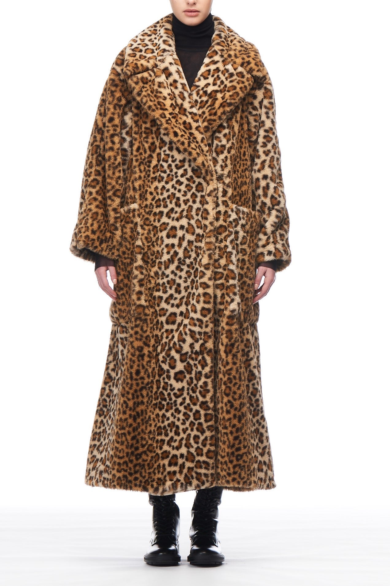 Wearing the Fuzzi Woman Leopard Print Coat, a person stands facing the camera. This vintage piece from Fuzzi showcases a wide collar and large pockets, complemented by sleek black boots against a plain white background.