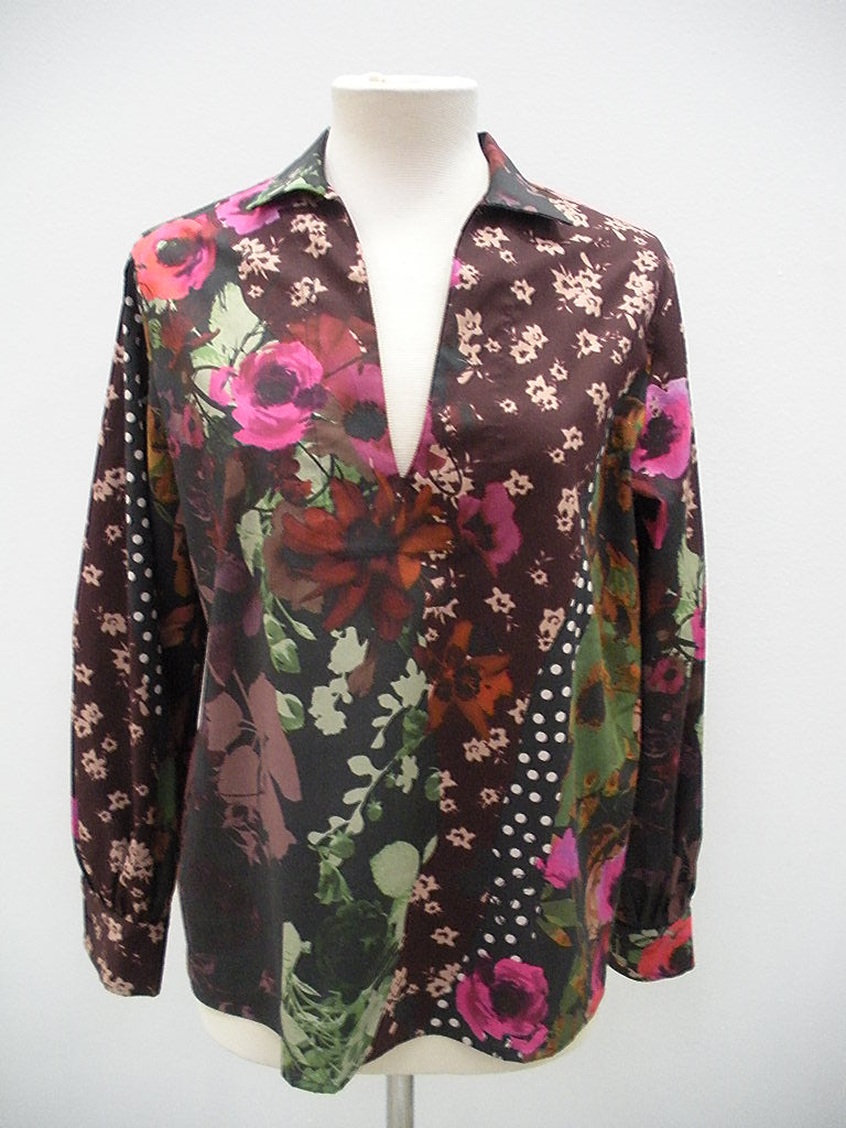 Displayed on a mannequin is the Fuzzi Woman Floral Print Shirt by Fuzzi, featuring a bohemian flair with a deep V-neck, designed with a mix of pink and red flowers, green leaves, and small white flowers set against a dark background accented with polka dots.