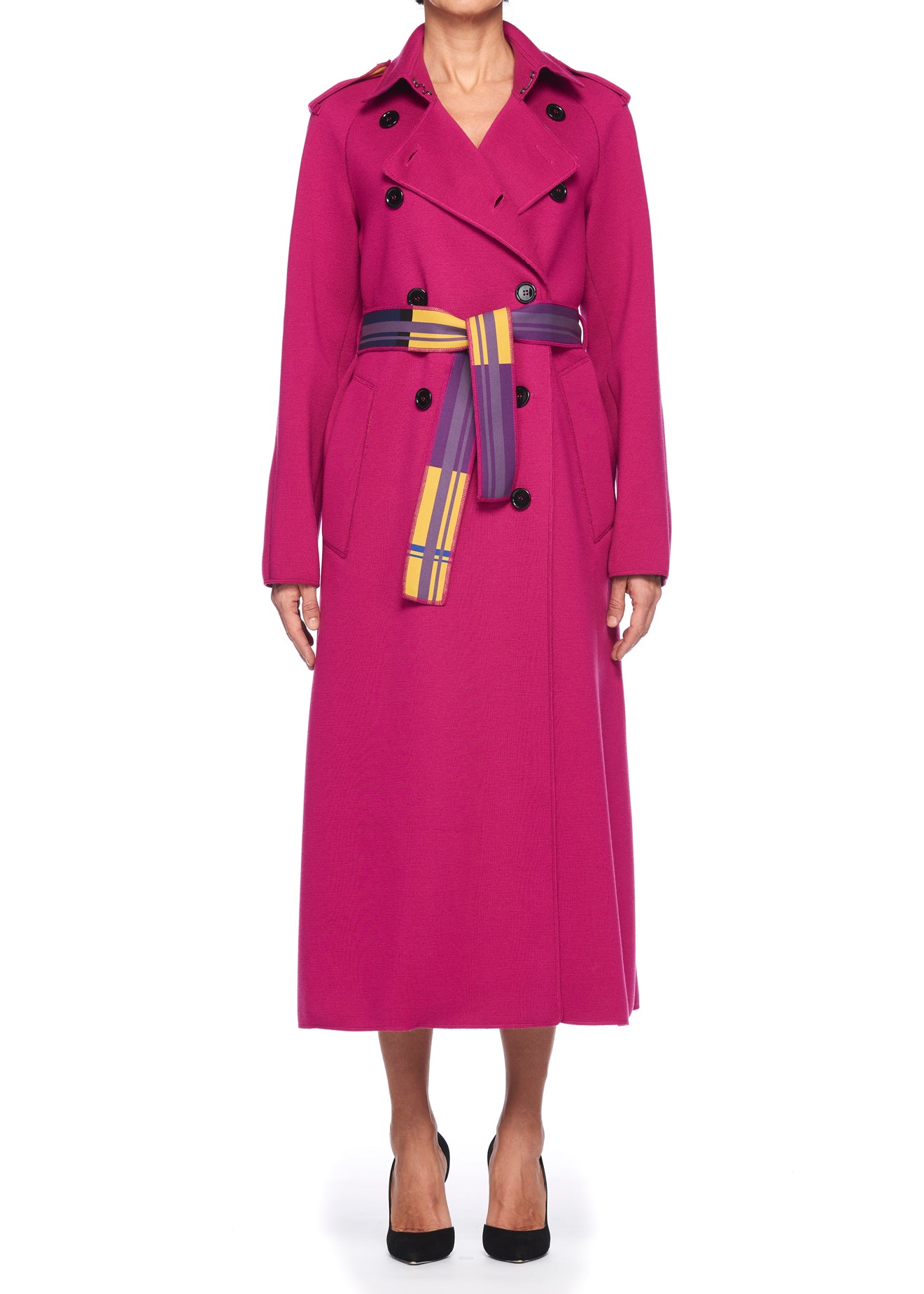 A person wearing the Fuzzi Woman Double-Breasted Trench Coat with Scarf Belt, featuring a vibrant pink design with black buttons and a multicolored belt, stands poised against a plain white background, paired effortlessly with sleek black heels.