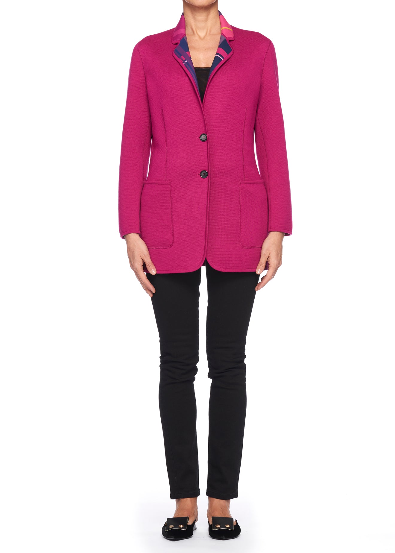 A person wearing the Fuzzi Woman Reversible Wool Blazer in bright pink, featuring two front pockets, along with black pants and black shoes. The vintage piece from Fuzzi is buttoned with two buttons, while the collar reveals a hint of a patterned lining. The person stands against a plain white background.