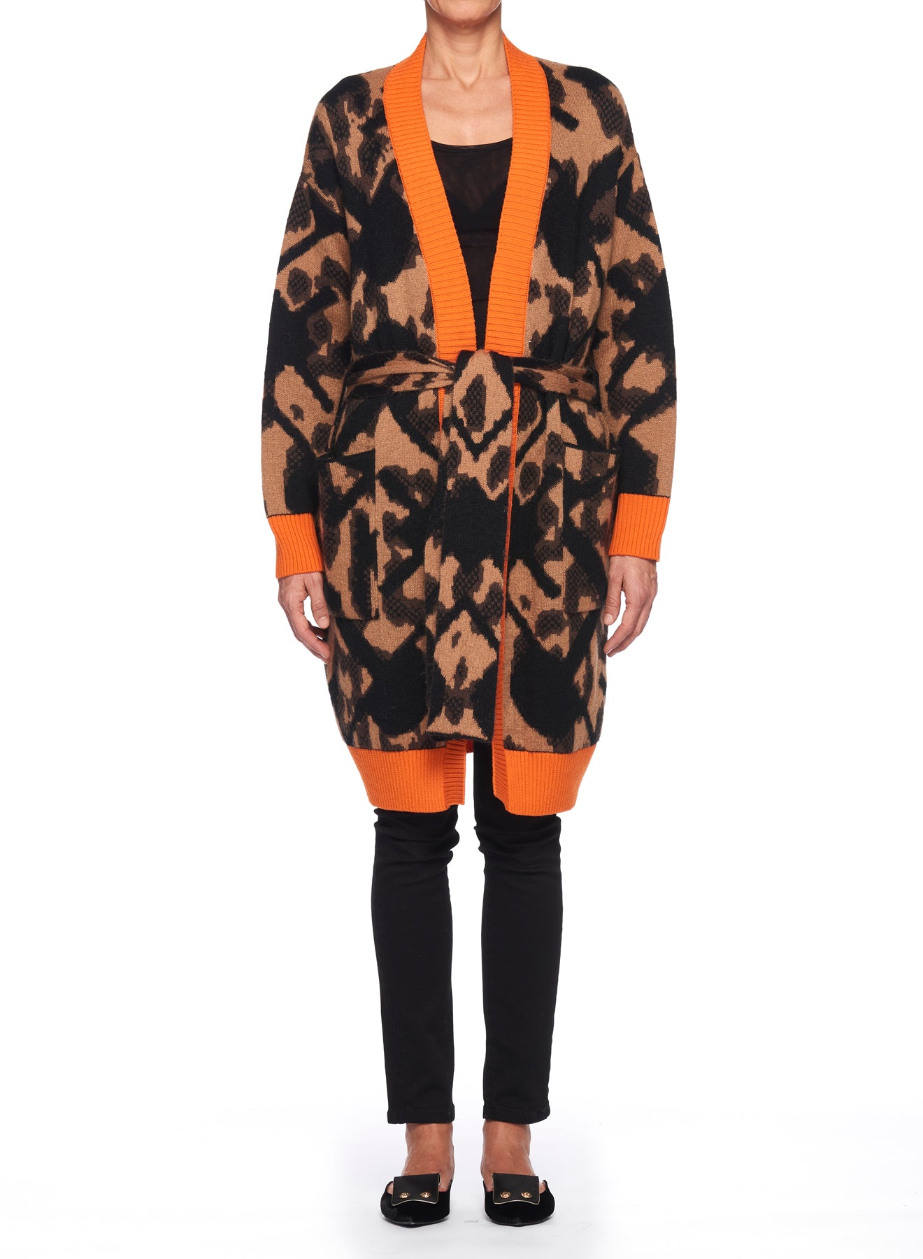 A person wearing the Fuzzi Woman Bold and Cozy Coat, a vintage-inspired leopard-print piece with orange trim, tied at the waist. They pair it with black pants and shoes. This cozy coat's bold pattern adds a touch of style to their casual look.