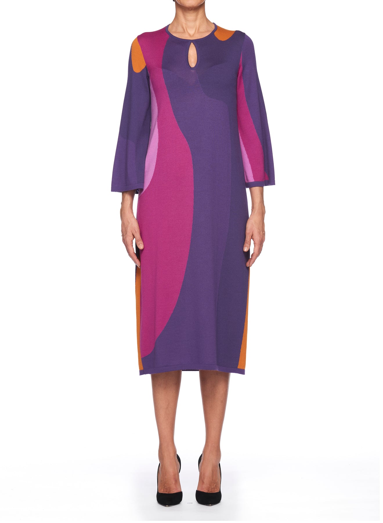 A person wearing the Fuzzi Woman Retro Vibes Dress, a long-sleeved, knee-length retro dress from Fuzzi, showcases an abstract pattern of purple, pink, and orange shapes. The dress features color-blocking details and a small keyhole opening near the neckline. The person is standing against a plain white background.