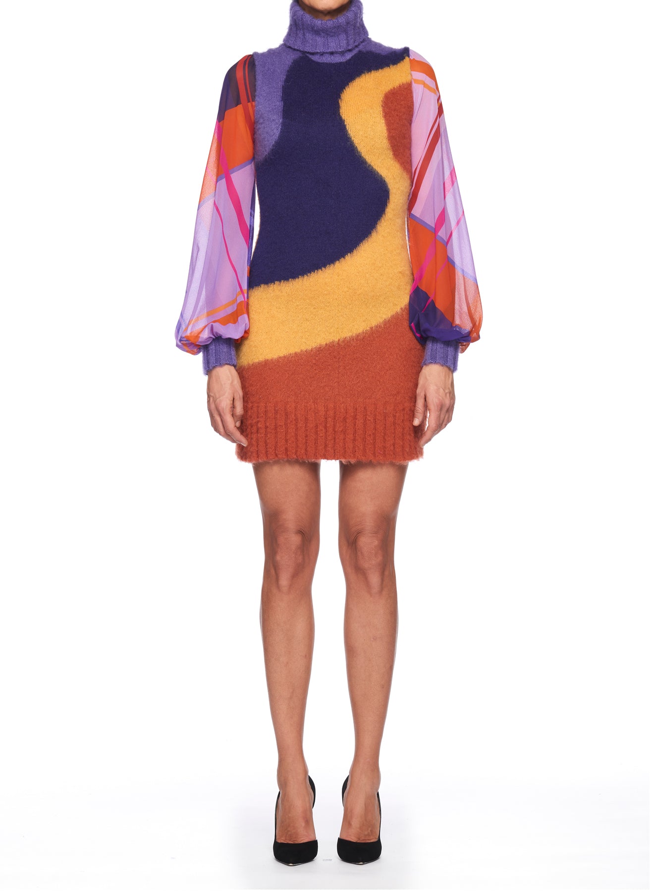 A person is dressed in the Fuzzi Woman Bold and Colorful Mini Dress by Fuzzi, showcasing a vibrant knit design with abstract swirls in purple, yellow, and orange. The dress has long, semi-transparent patterned sleeves and features a turtleneck. They are standing against a plain white background.