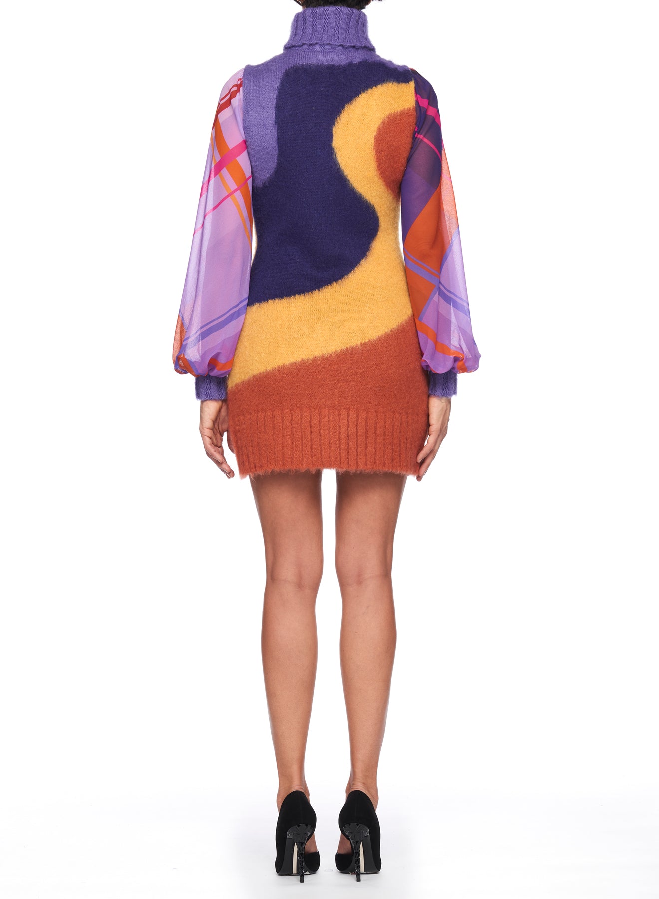 Rear view of a person wearing the Fuzzi Woman Bold and Colorful Mini Dress by Fuzzi, featuring abstract patterns in purple, yellow, and orange. The dress is designed with sheer sleeves showcasing pink, orange, and purple plaid designs. The look is completed with chic black high heels.