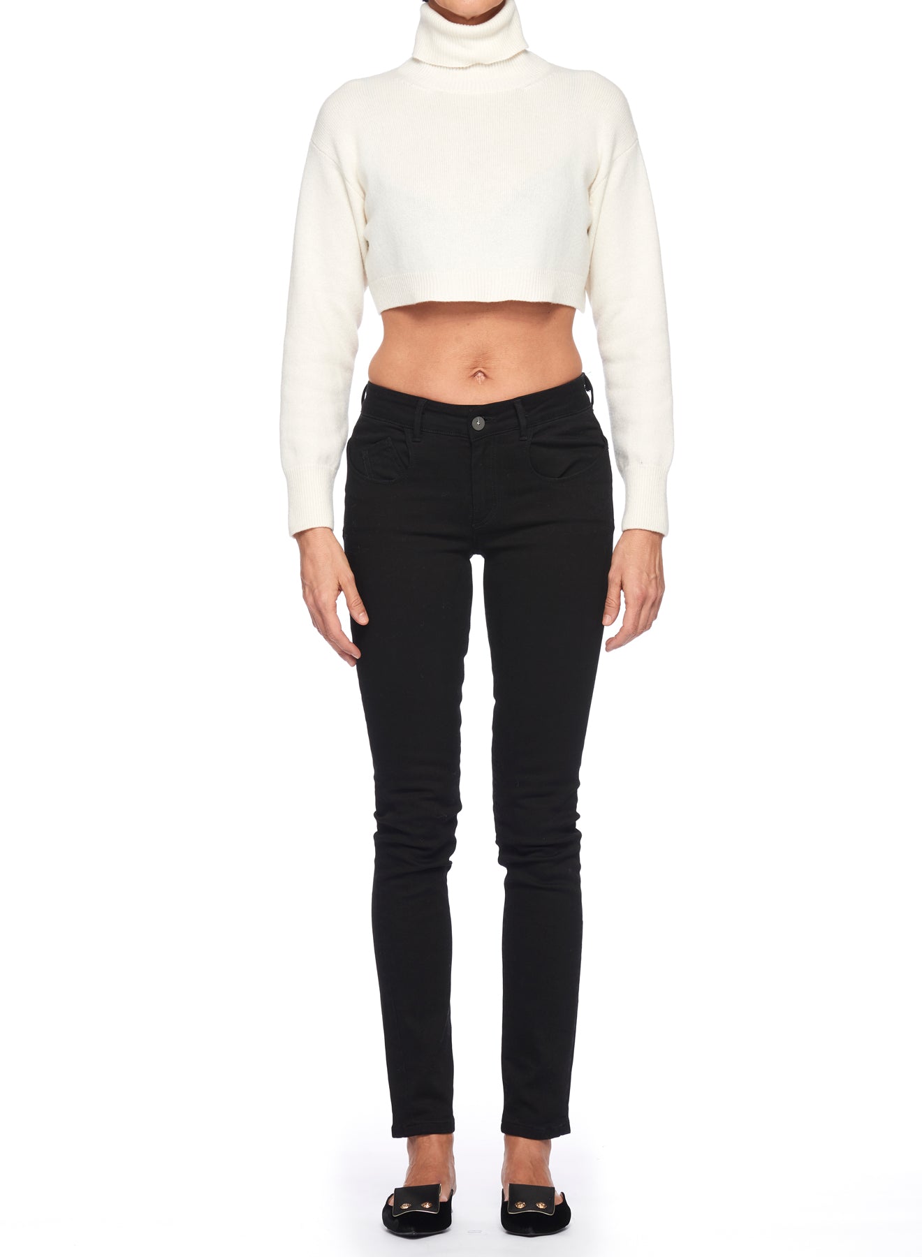 A person wearing the Fuzzi Woman Textured Cropped Sweater in white pairs it with black pants while standing against a plain white background. The outfit is completed with black slip-on shoes, creating a minimalist yet stylish look.