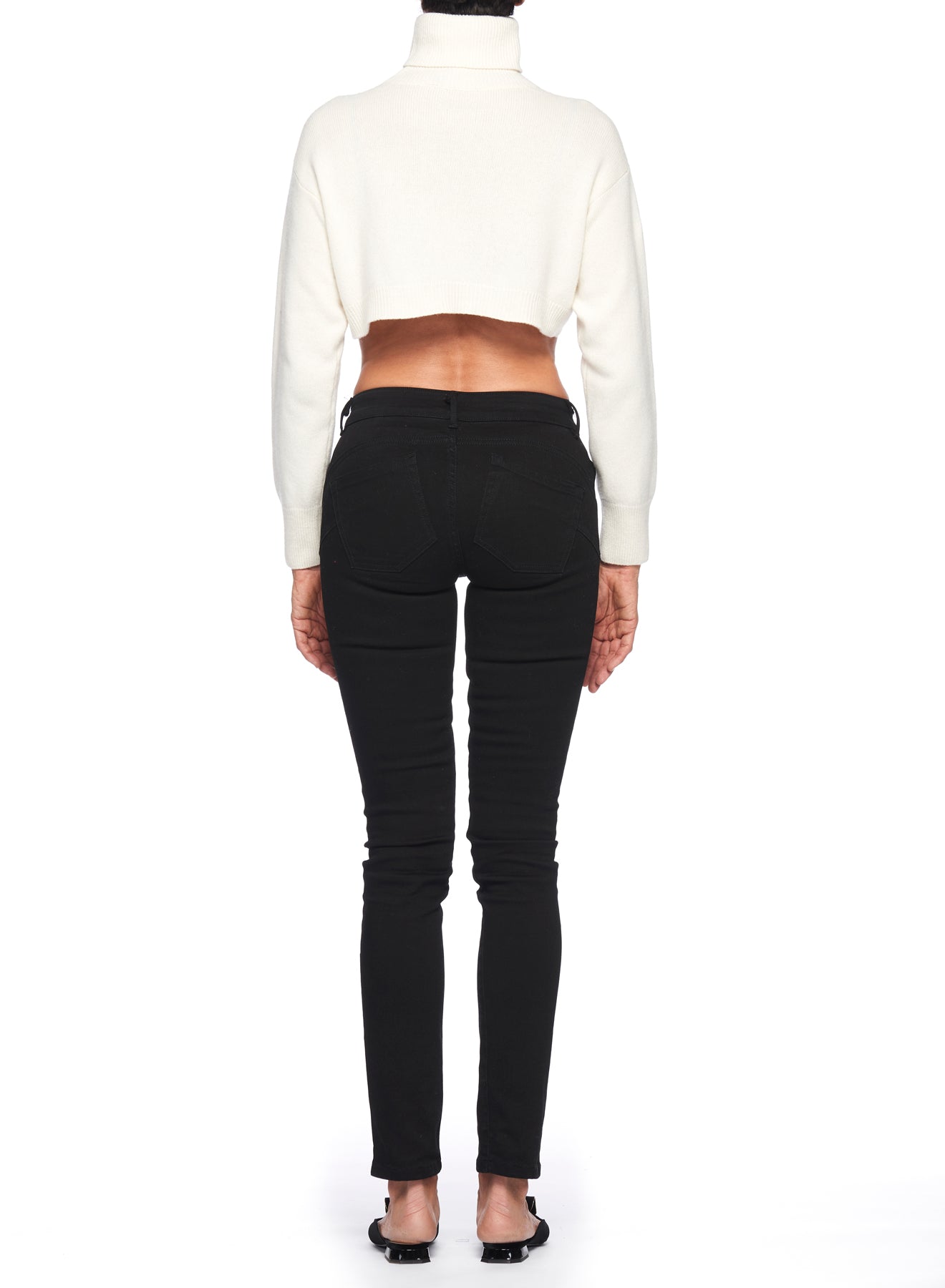 Rear view of a person wearing a vintage piece—a Fuzzi Woman Textured Cropped Sweater—paired with black skinny jeans and black shoes, standing against a white background.