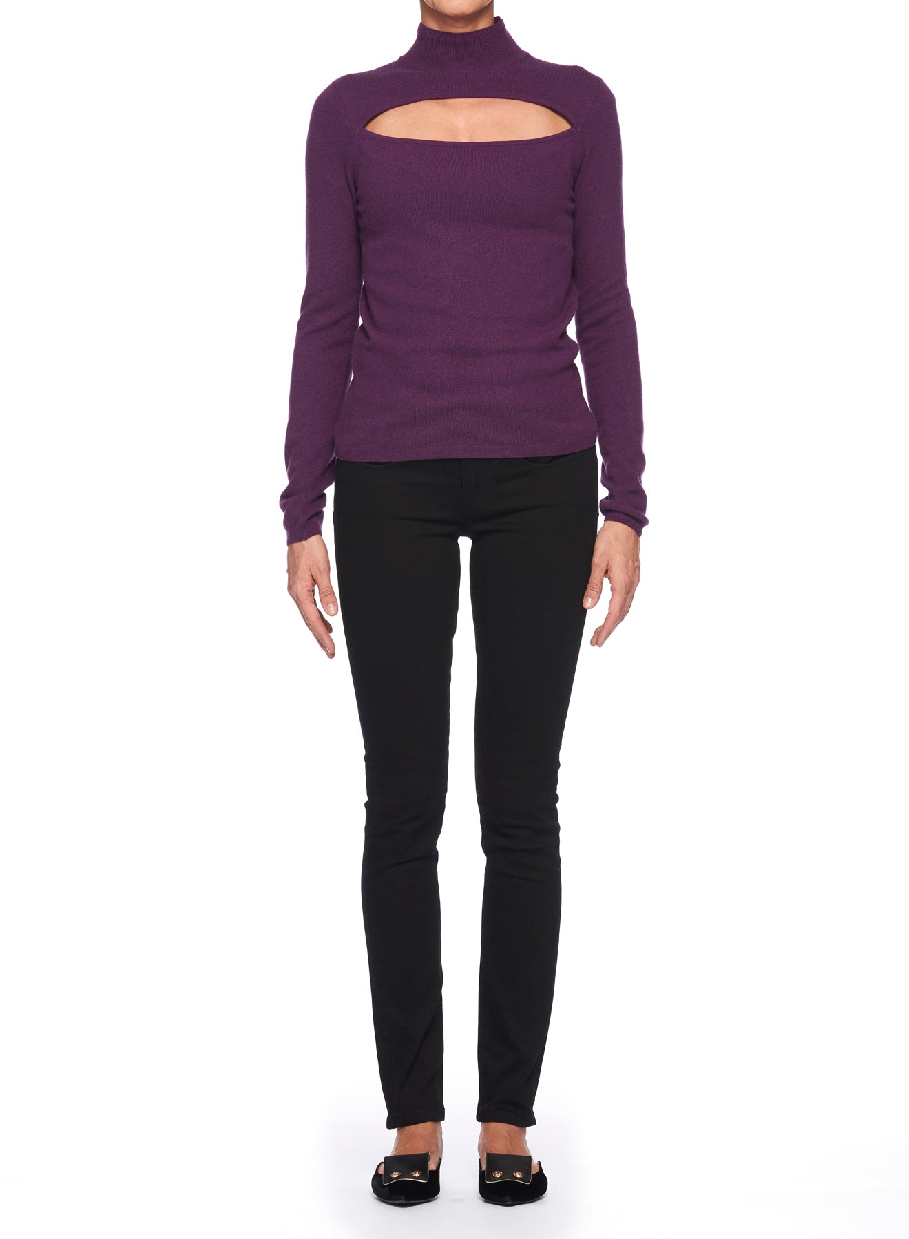 A person is wearing the Fuzzi Woman Edgy Cutout Turtleneck, a purple ribbed knit sweater from Fuzzi, featuring a high neckline and a rectangular cutout across the chest. They have paired it with black pants and black shoes, standing against a plain white background and exuding a touch of vintage elegance.