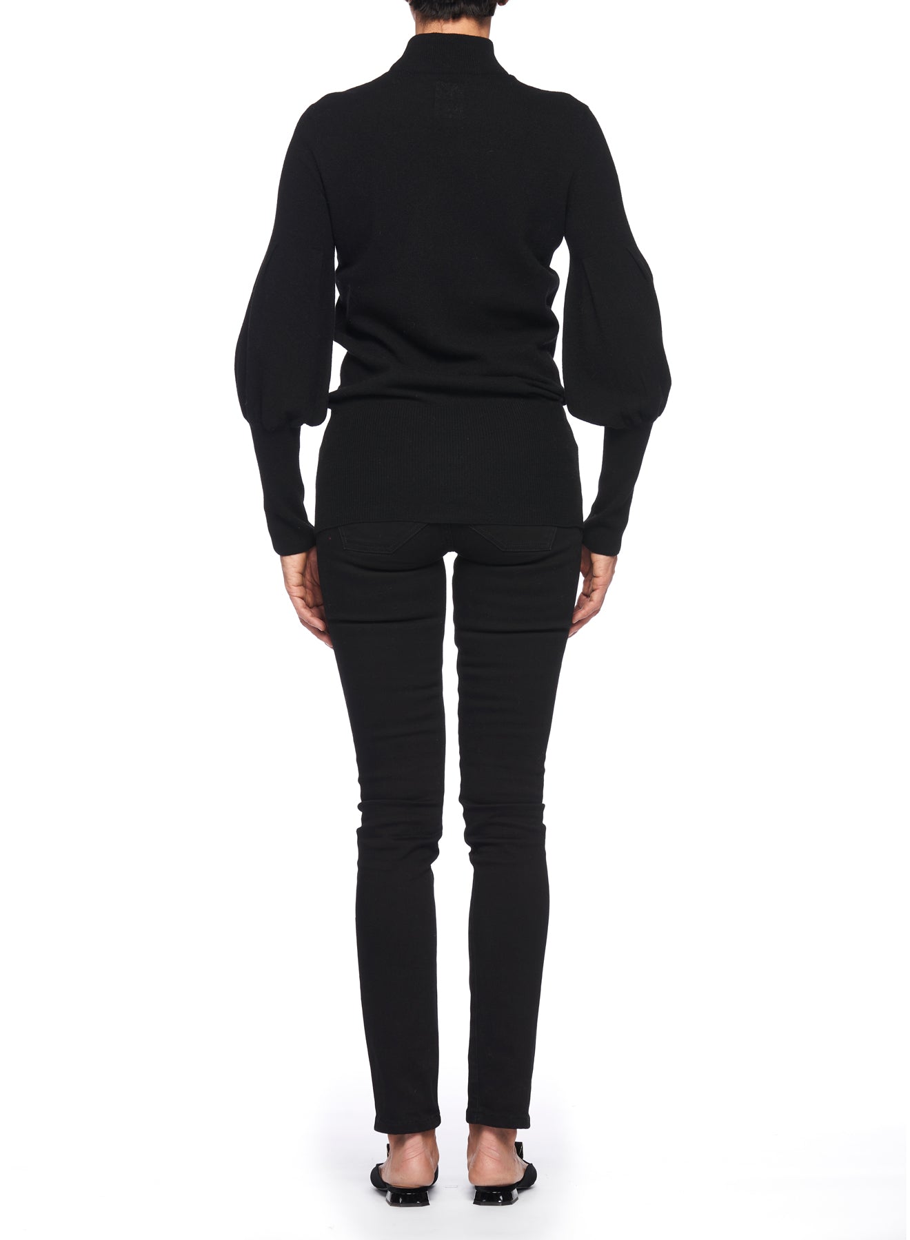 A person wearing a Fuzzi Woman Black V-Neck Sweater with Puff Sleeves, crafted from knit fabric, and black pants stands facing away from the camera against a white background. They are also wearing open-toed black shoes.