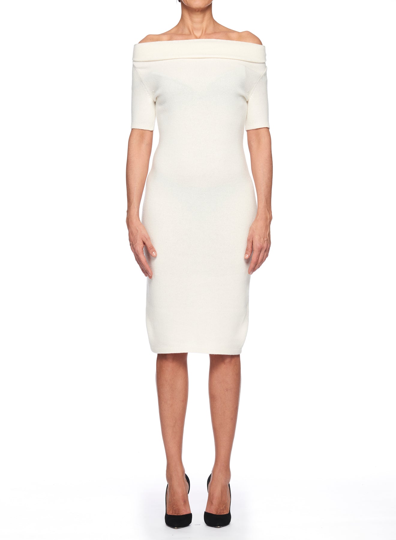 A person stands facing forward in a Fuzzi Woman White Cowl Neck Dress, knee-length and made of ribbed knit fabric. The dress features an off-the-shoulder design with short sleeves, paired perfectly with sleek black heels, all set against a crisp white background.