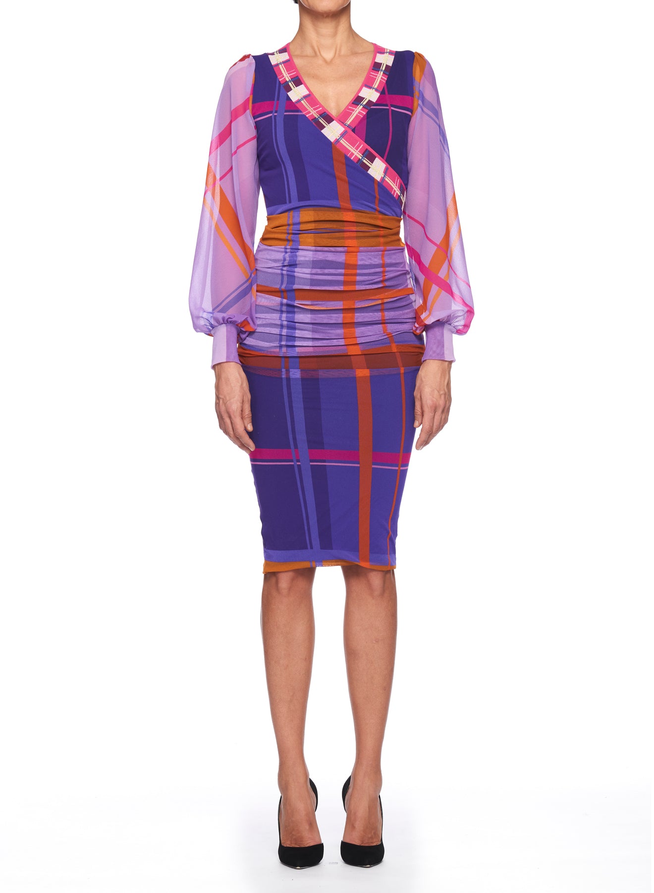 A person wearing the Fuzzi Woman Colorful Dress with Sheer Sleeves from the Fuzzi brand stands against a white background. This knee-length vintage piece showcases sheer long sleeves and a vibrant plaid pattern in shades of purple, pink, blue, and orange. It features a wrap-style top with ruching at the waist, perfectly paired with classic black heels.