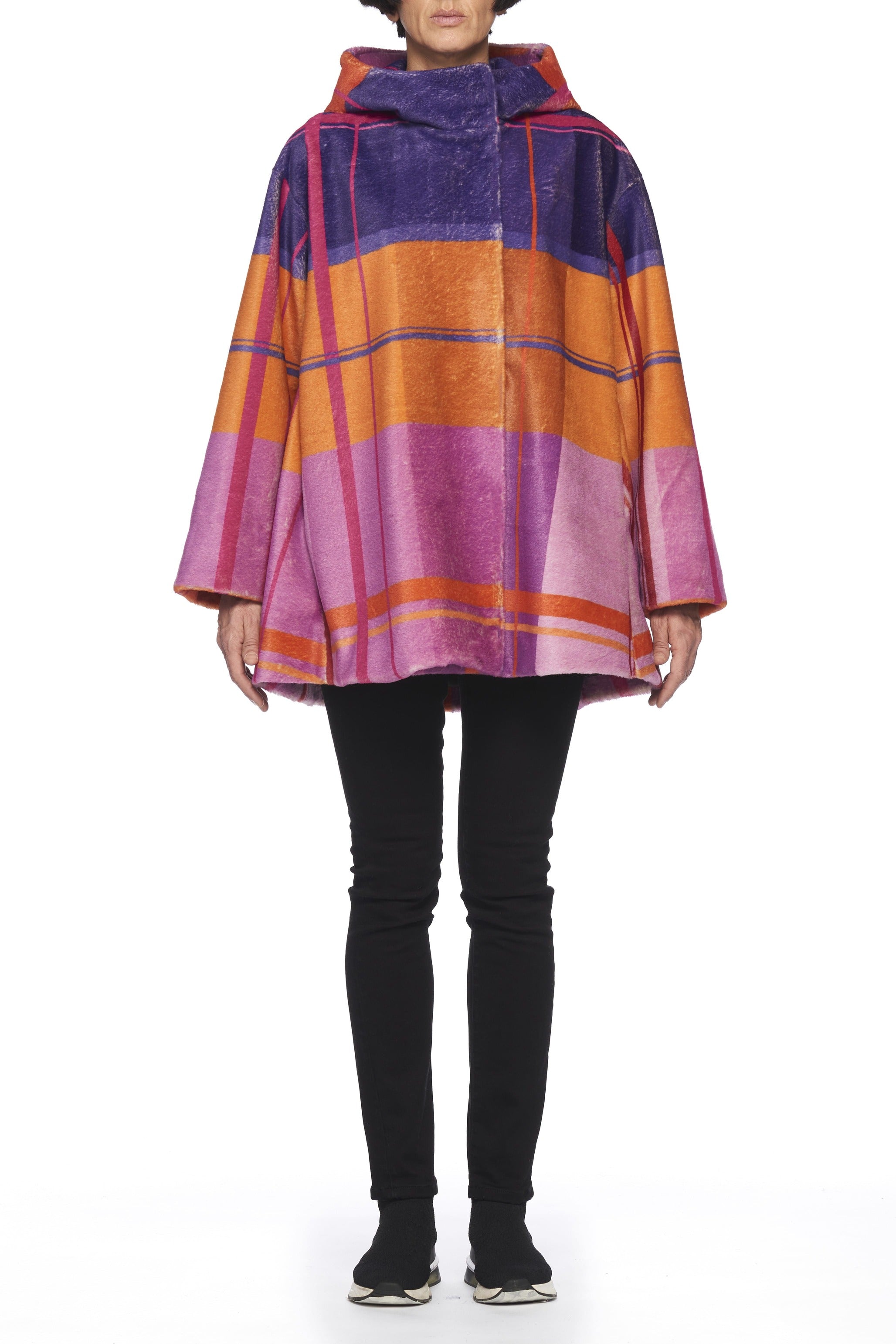 A person wears the Fuzzi Woman Colorful Oversized Coat, featuring bold stripes in shades of pink, orange, and purple against a plain white background. With its wide sleeves and relaxed fit, this vintage piece by Fuzzi perfectly complements their black pants and shoes.