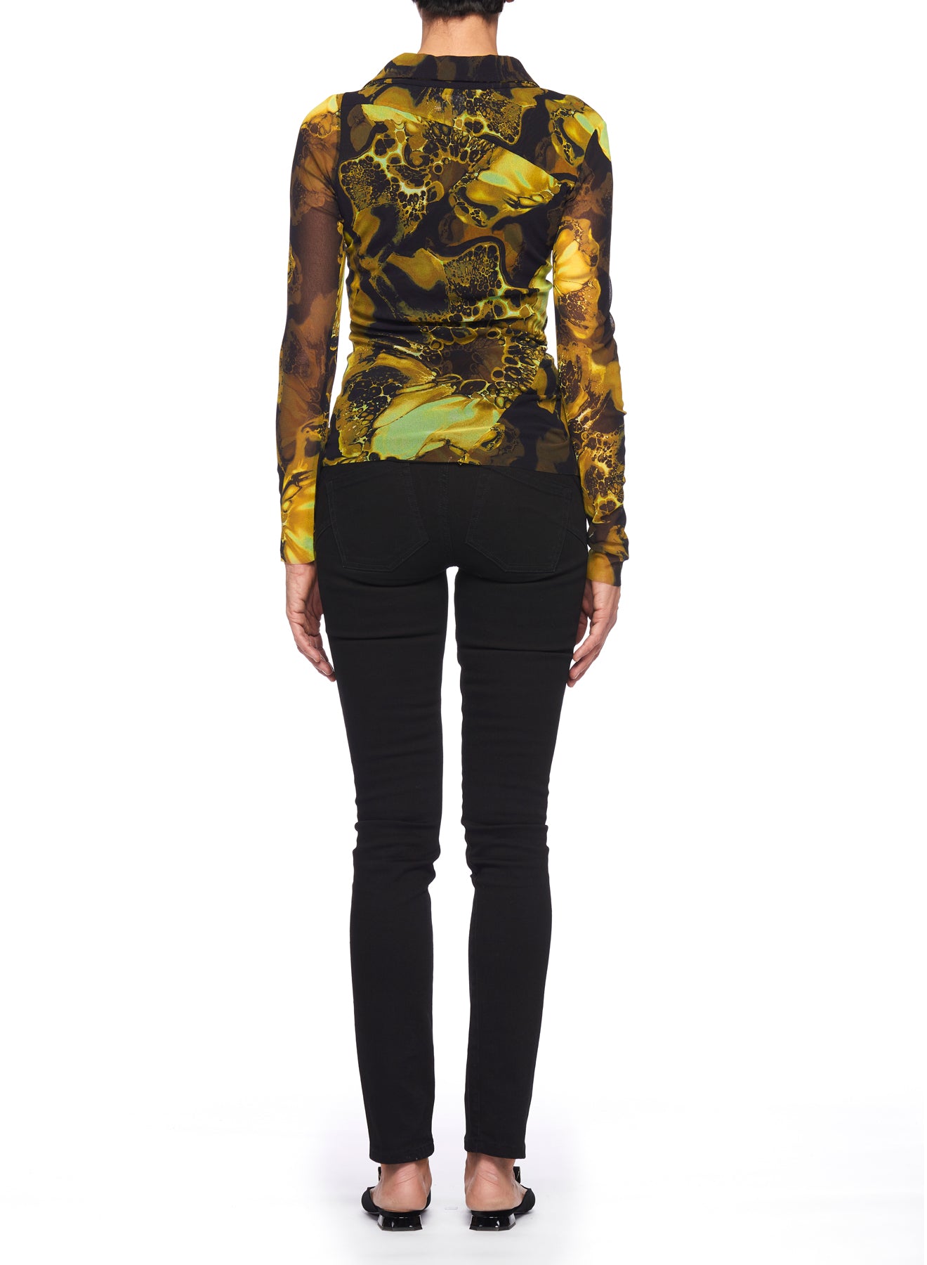 A person stands facing away, wearing a Fuzzi Woman Print Mesh Top with V-Neck featuring a yellow and black abstract print, paired with black pants and shoes, set against a white background.