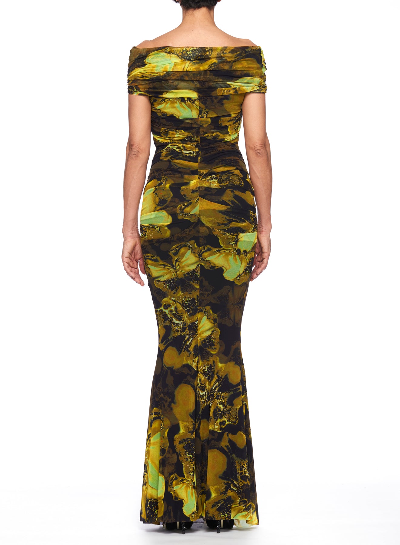 A person wearing the Fuzzi Woman Maxi Dress with a mermaid silhouette showcases a vibrant, abstract green and yellow floral pattern. This vintage piece is form-fitting and floor-length, offering a straight back view against a plain white background.