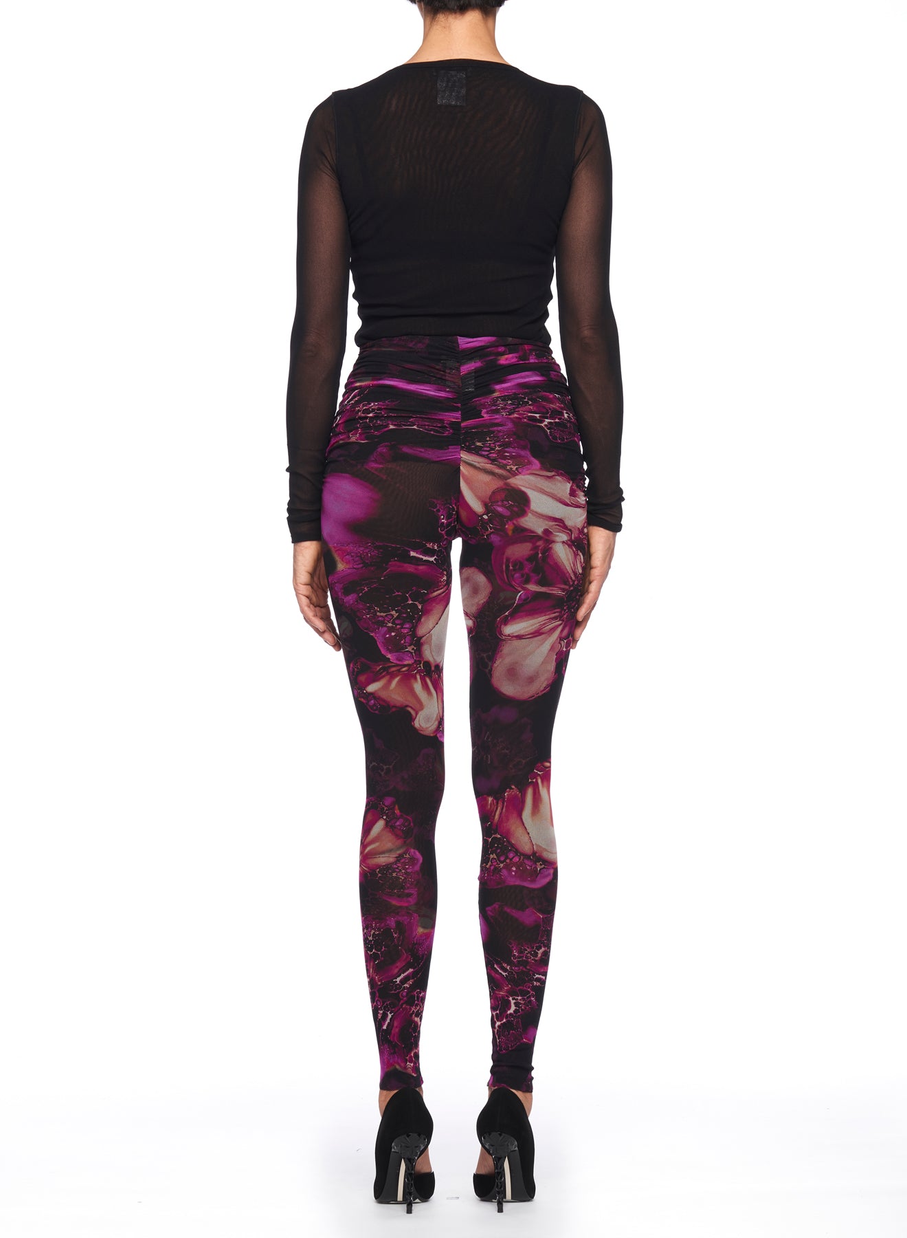 A person wearing a black long-sleeve top pairs it with the Fuzzi Woman Leggings from Fuzzi, showcasing an intricate abstract floral print. Black high-heeled shoes complete the ensemble, all against a plain white background.