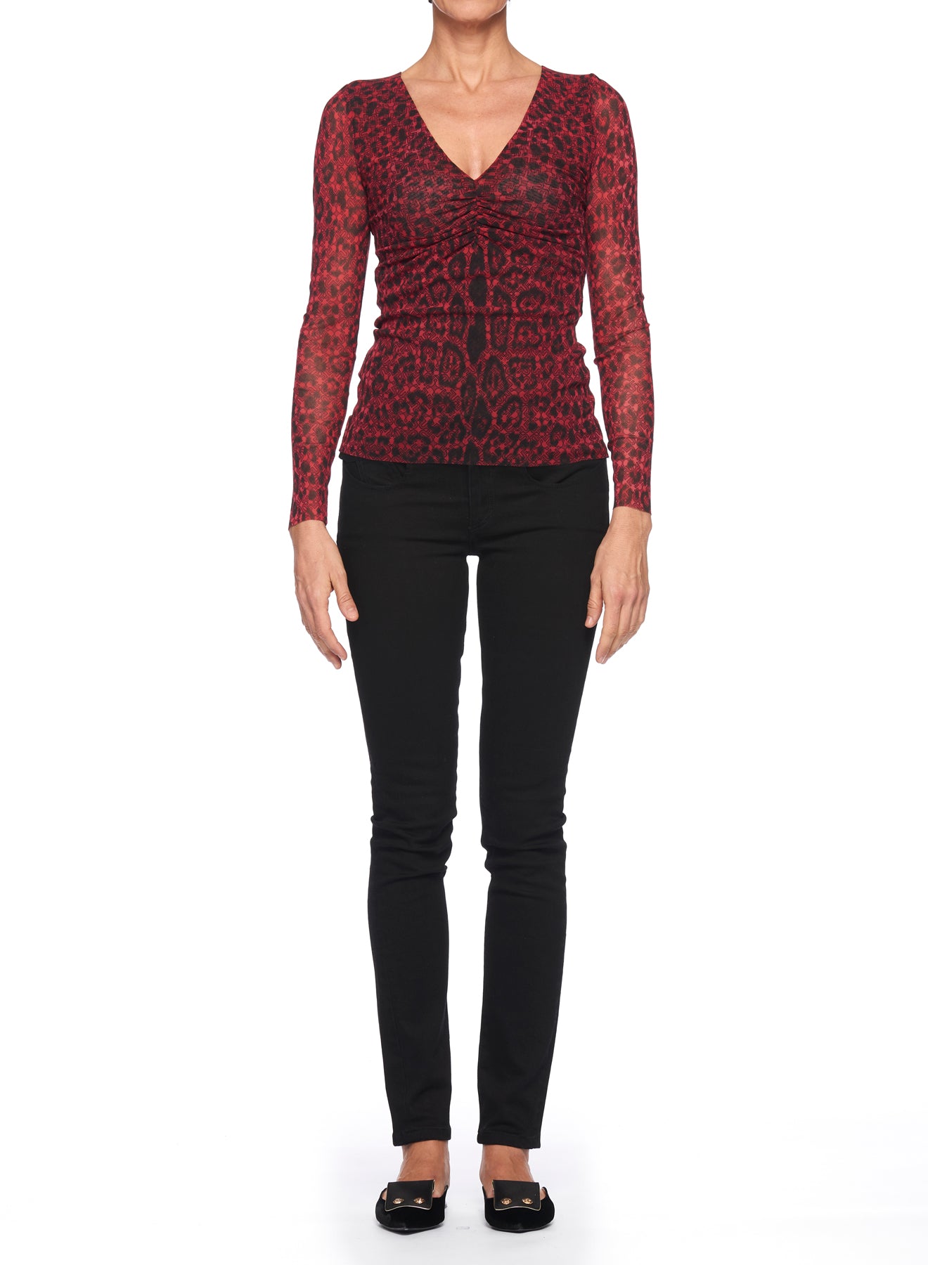 A person stands against a white background wearing the striking Fuzzi Woman Leopard Print Mesh Top, complemented by black pants and black flats. The sheer fabric of the Fuzzi top adds an elegant touch to the ensemble, while the individual maintains a relaxed posture with arms by their sides.