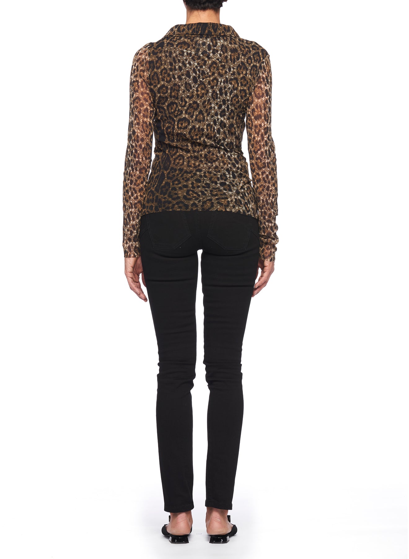 A person stands with their back to the camera, wearing the Fuzzi Woman Edgy Leopard Print Mesh Top paired with black skinny pants. They have on black open-toe shoes against a plain white background.