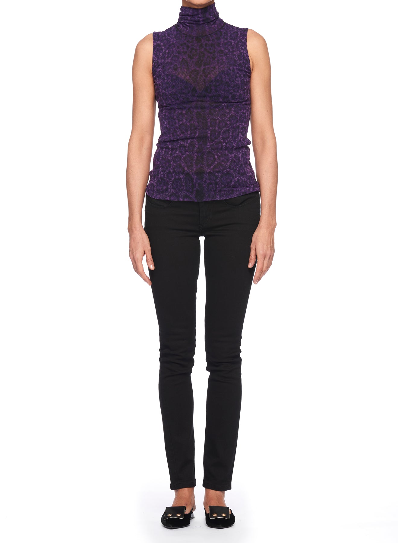 A person wearing the Fuzzi Woman Top, a sleeveless high-neck design by Fuzzi, in a purple pattern stands against a white background. They pair it with black skinny pants and black shoes, with their hands relaxed by their sides.