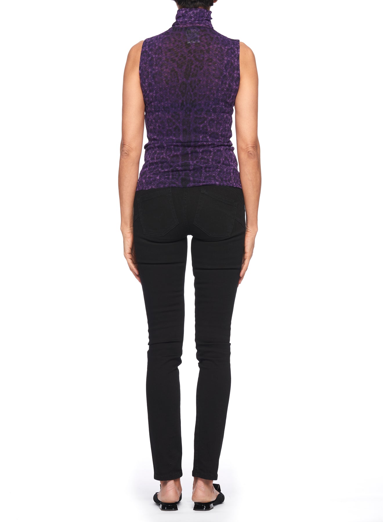 Back view of a person wearing a Fuzzi Woman Top with a high neckline and sleeveless design featuring a purple leopard print, paired with black pants. This vintage piece pops against the plain white background and is complemented by black shoes.