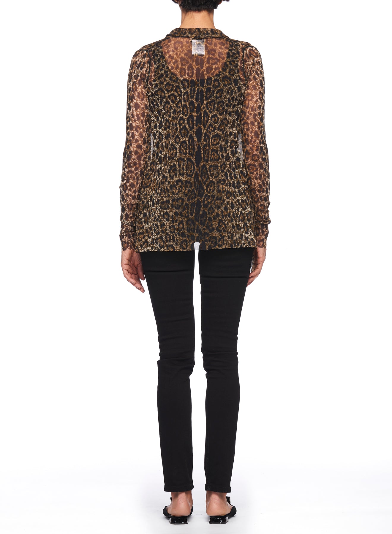 A person is dressed in the refined Fuzzi Woman Leopard Print Mesh Cardigan, featuring sheer long sleeves. They pair this striking top with black pants and sandals, posing with their back to the camera against a simple white backdrop.