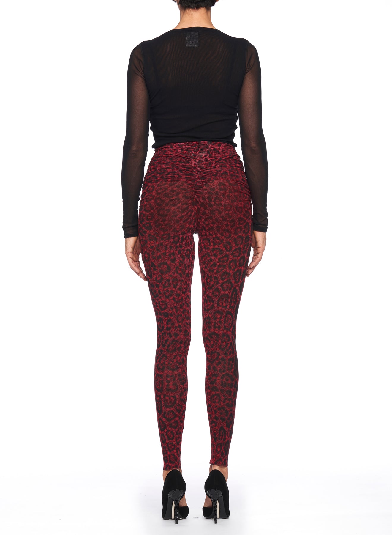 A person stands with their back to the camera, wearing a sheer black long-sleeve top and high-waisted Fuzzi Woman Leopard Print Pants from Fuzzi. They complete the chic look with black high-heeled shoes against a plain white background.