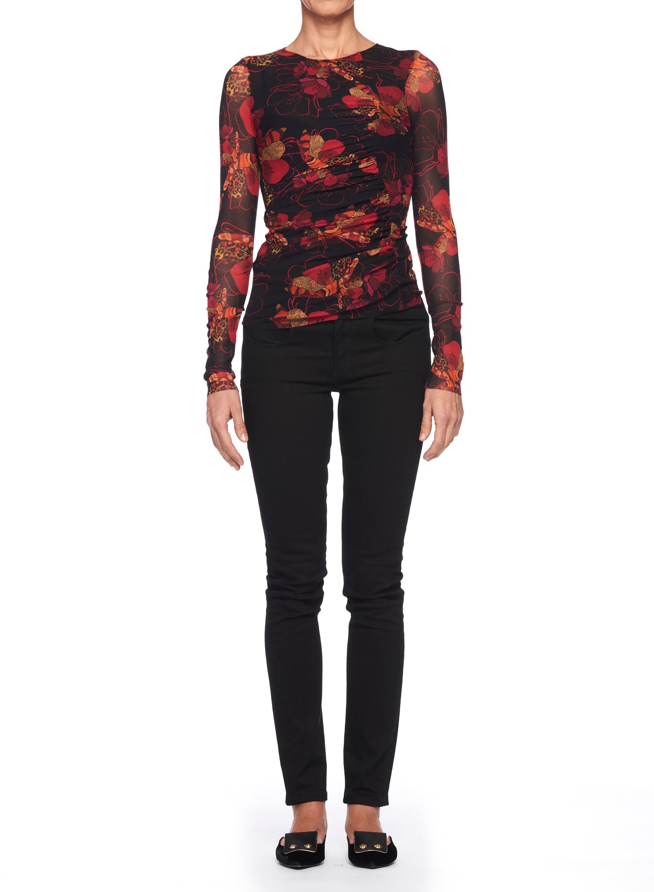 A person is dressed in a Fuzzi Woman Floral Print Mesh Top, featuring red and black hues, paired with black slim-fit pants and black flats. This vintage piece by Fuzzi stands out beautifully against the plain white background.