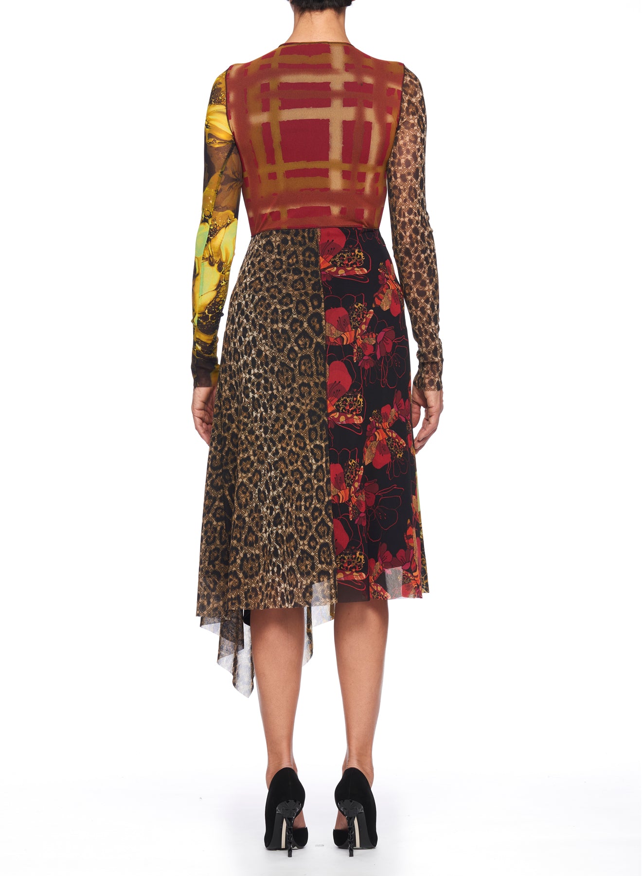 Rear view of a person wearing the Fuzzi Woman Mixed-Print Mesh Dress by Fuzzi, featuring a knee-length, asymmetrical hemline. The dress boasts a mix of patterns, including plaid on the bodice and floral sections on the skirt. The left sleeve showcases a yellow and brown pattern, while the right is adorned with animal print. They're complemented by black heels.