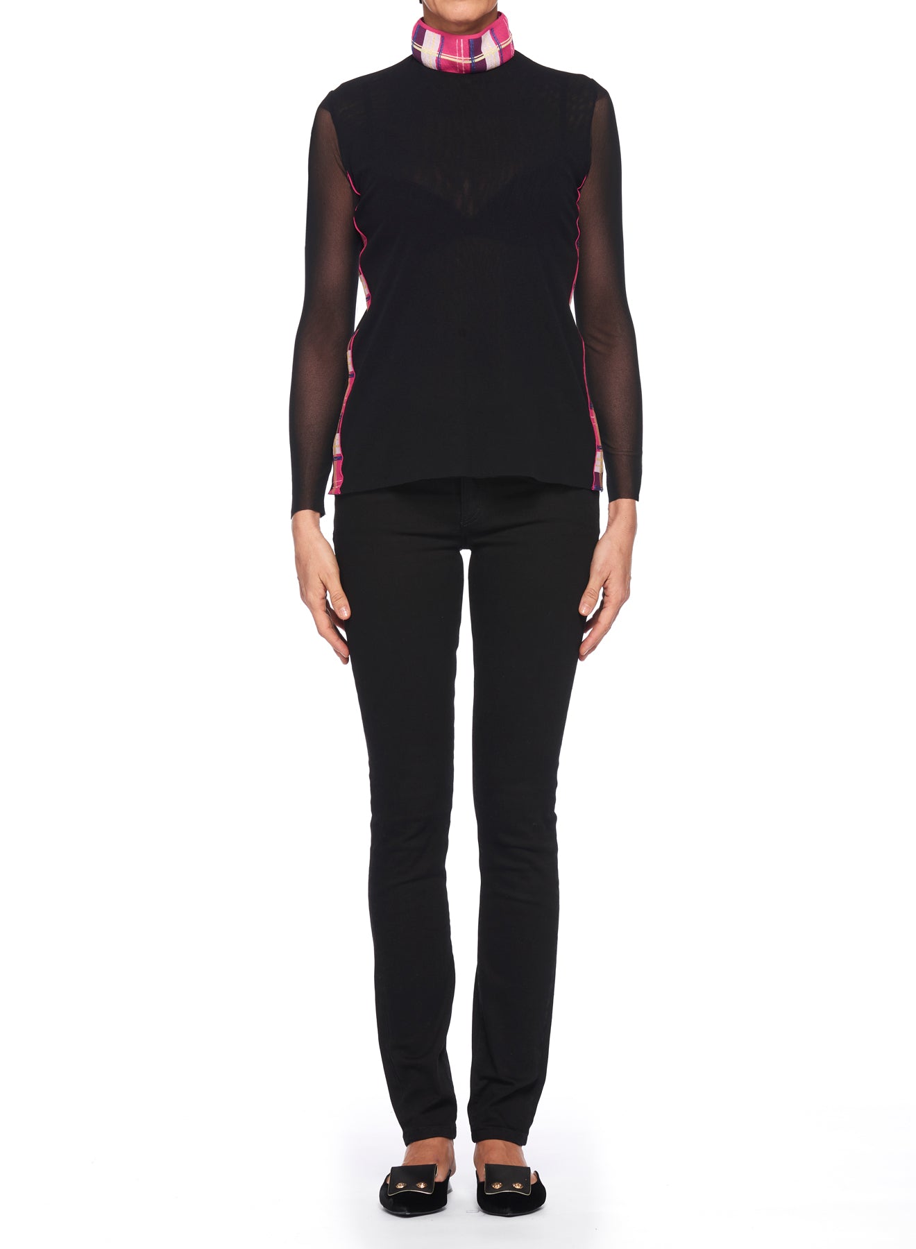 Against a white background, someone showcases the Fuzzi Woman Mesh-Sleeved Top by Fuzzi. This chic black outfit features sheer mesh sleeves and a high collar with pink plaid accents, evoking a vintage charm. The look is elegantly complemented by black pants and flats.